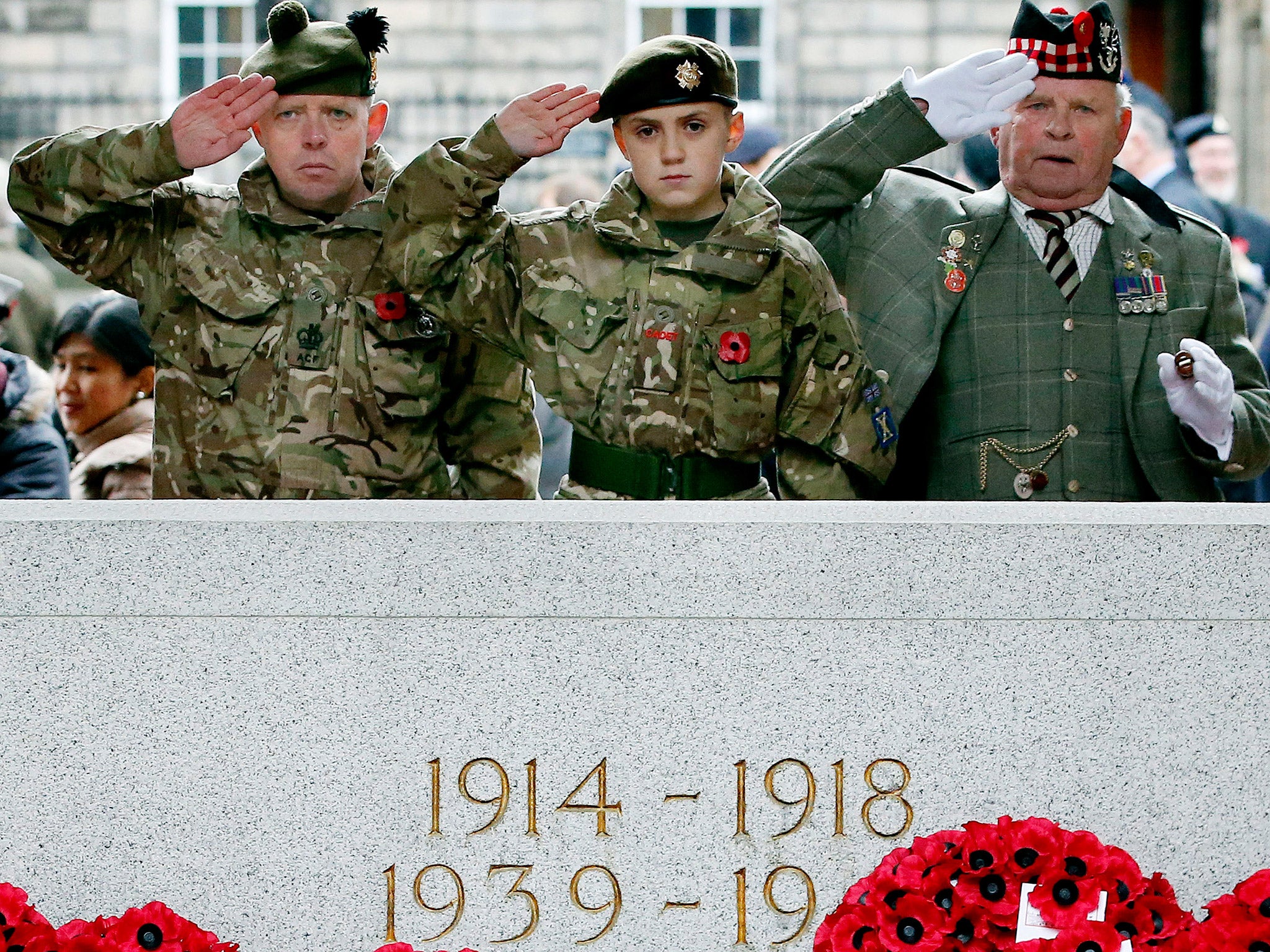 Three generations of the same family, Bob Munro (right) his son Andrew Munro (left), who both served in the Queen's Own Highlanders and Fraser, who is in the cadet force, salute the fallen PA