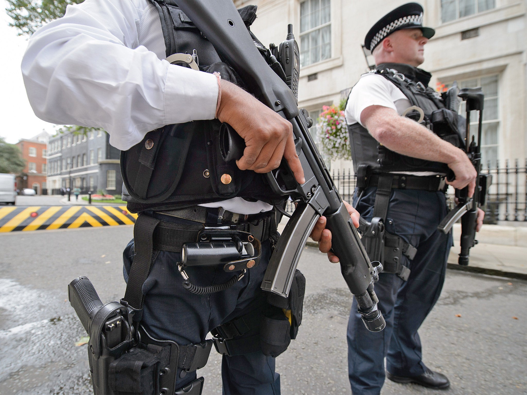 Armed police officers hold guns as they stand in Downing Street