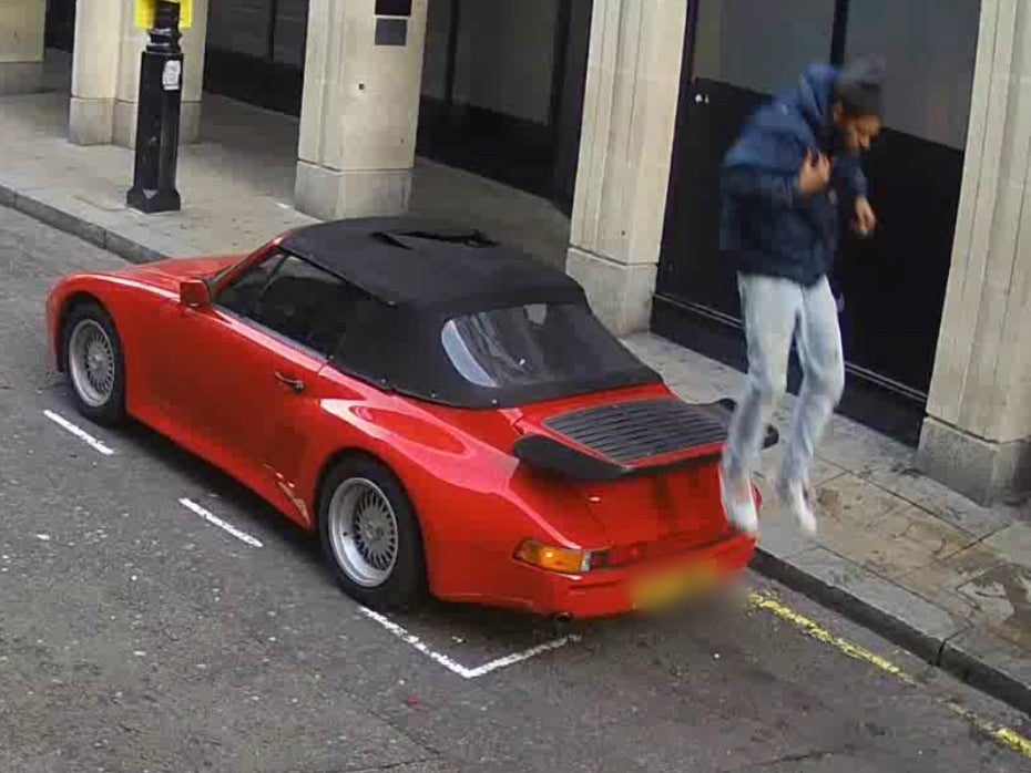 
The man hops off the car having climbed back through its slashed roof 