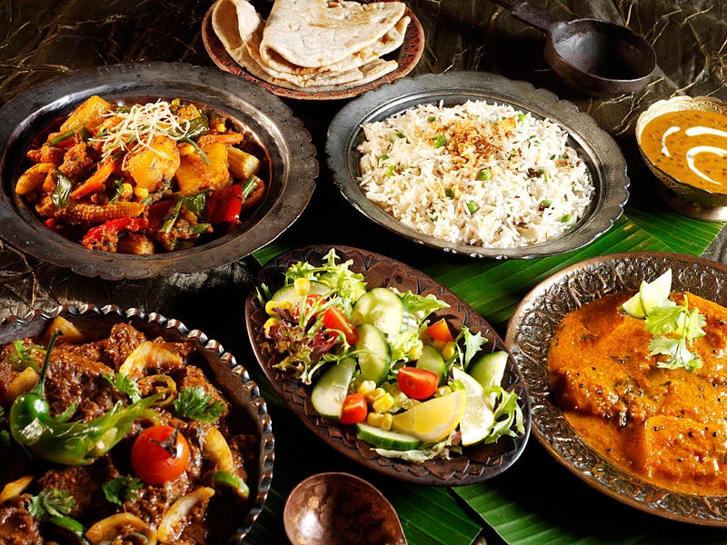 An Indian meal consisting of biryani, potato curry, chapathi and chicken