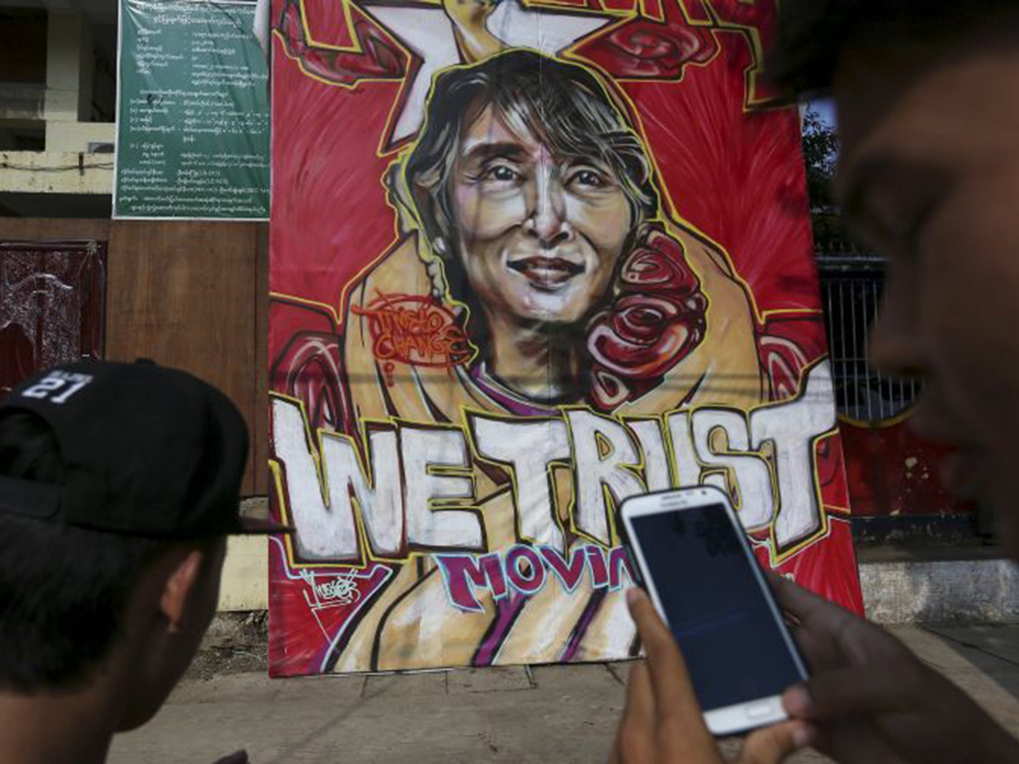 A supporter takes a picture of a graffiti of Aung San Suu Kyi in front of the National League for Democracy (NLD) head office