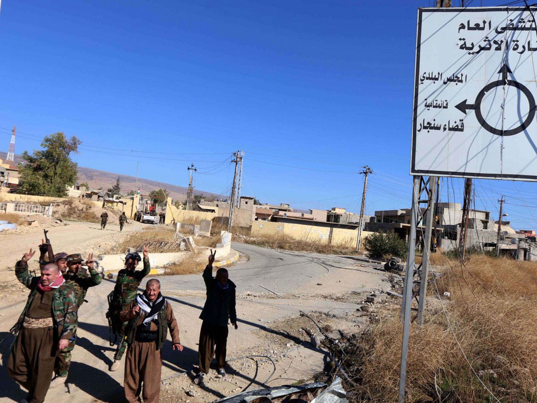 Kurdish Peshmerga forces flash the victory sign as they enter the northern Iraqi town of Sinjar