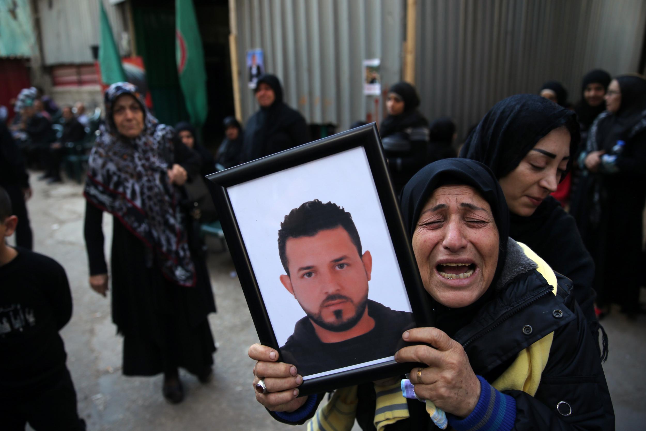 A relative of Samer Huhu, who was killed in a twin bombing attack in Beirut, waves his portrait