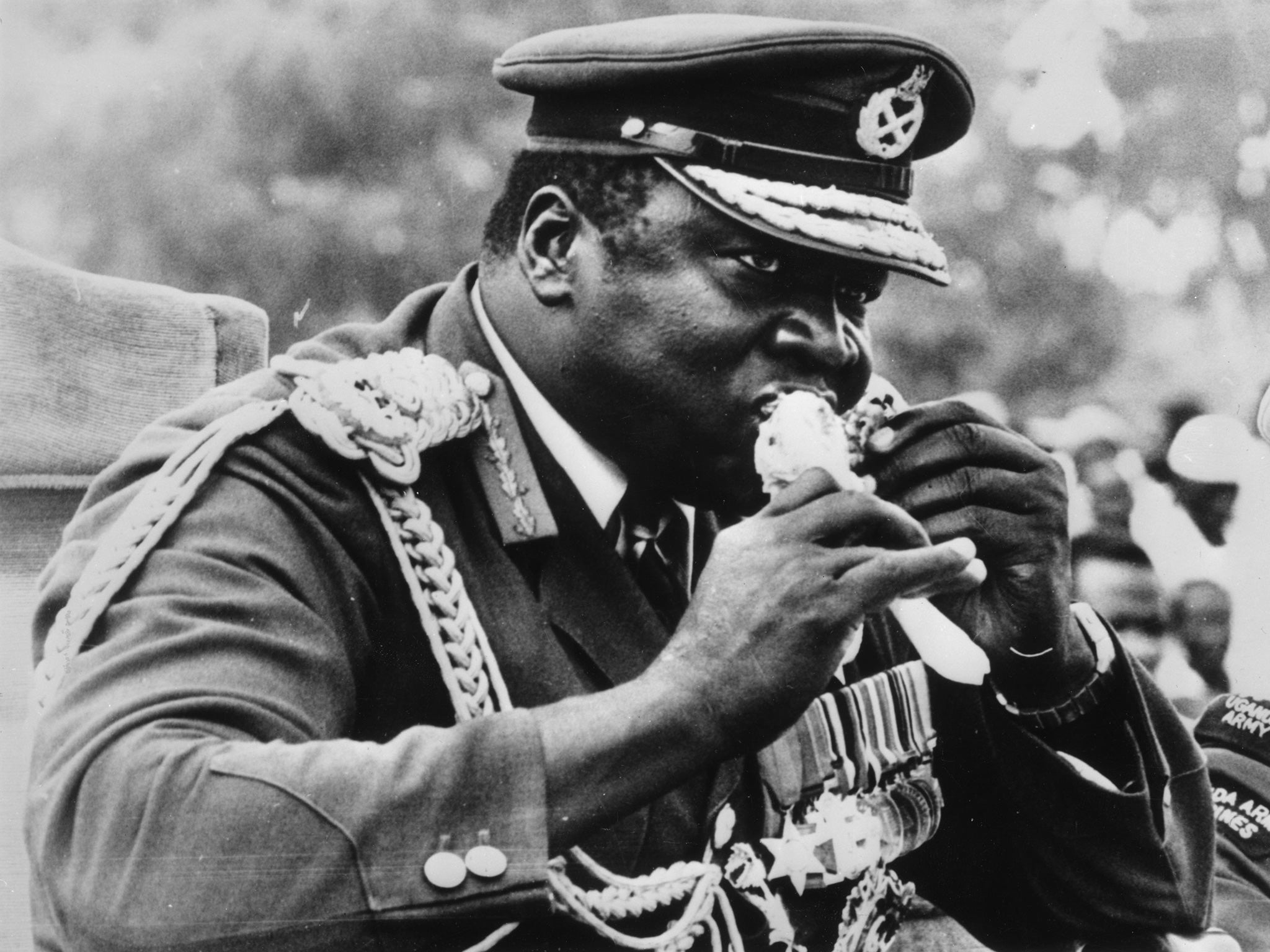 Idi Amin bites into a piece of chicken