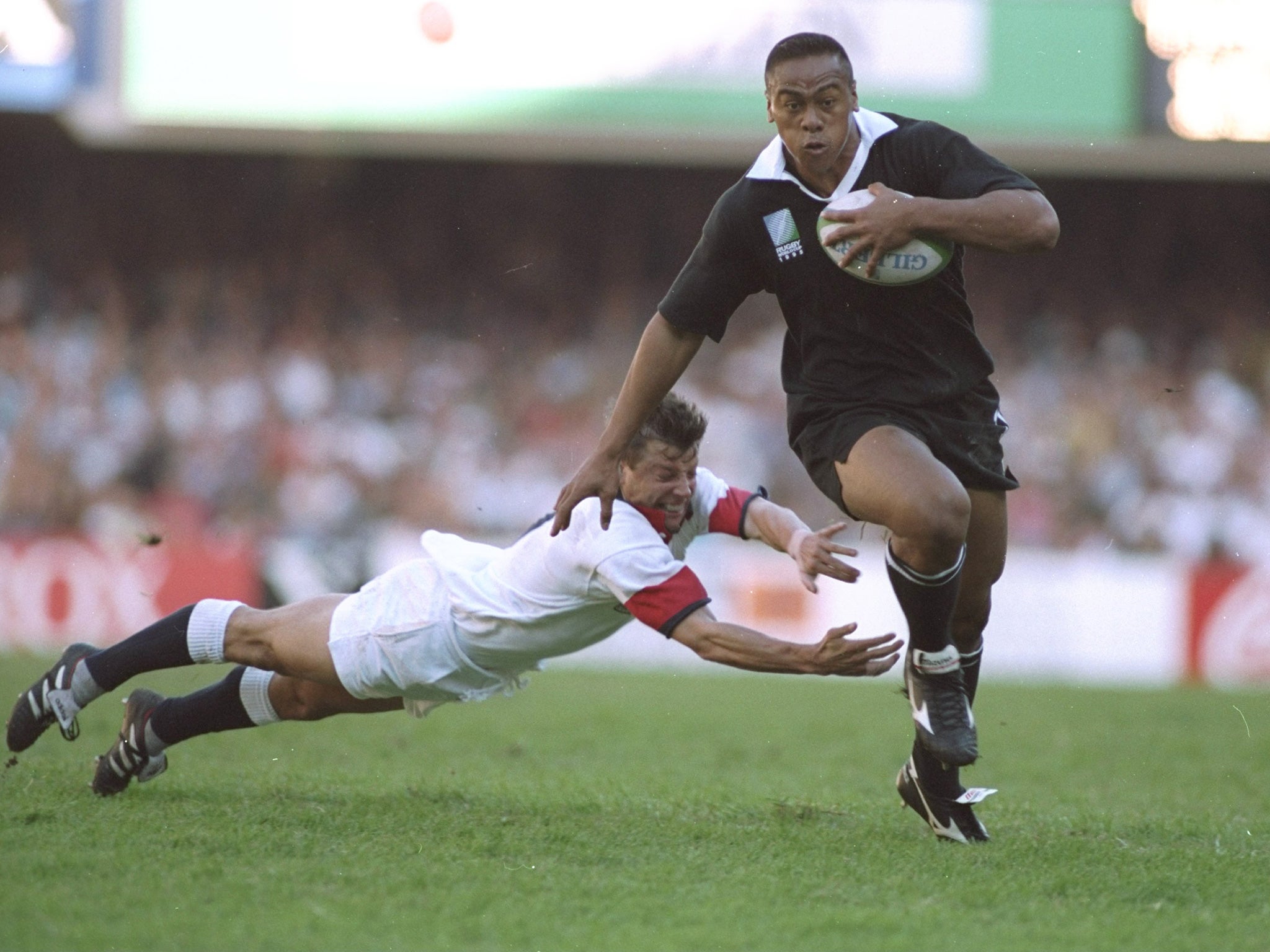 Lomu evades the diving tackle of Rob Andrew of England during the 1995 Rugby World Cup Semi Final