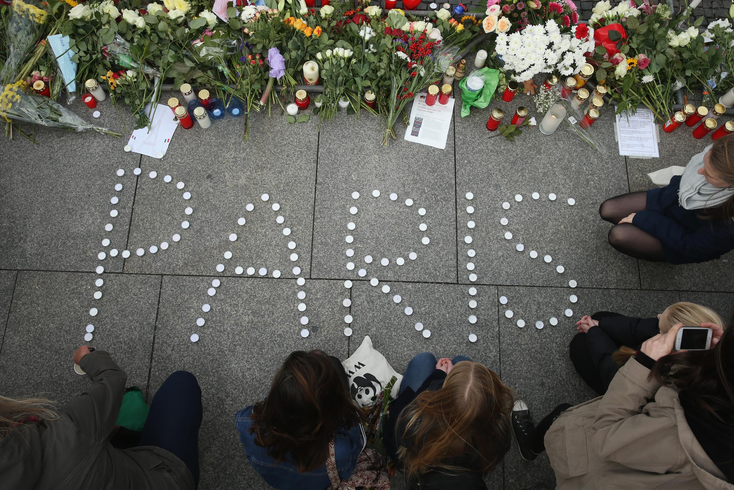 People lay flowers at the gates of the French embassy in Berlin following the attacks