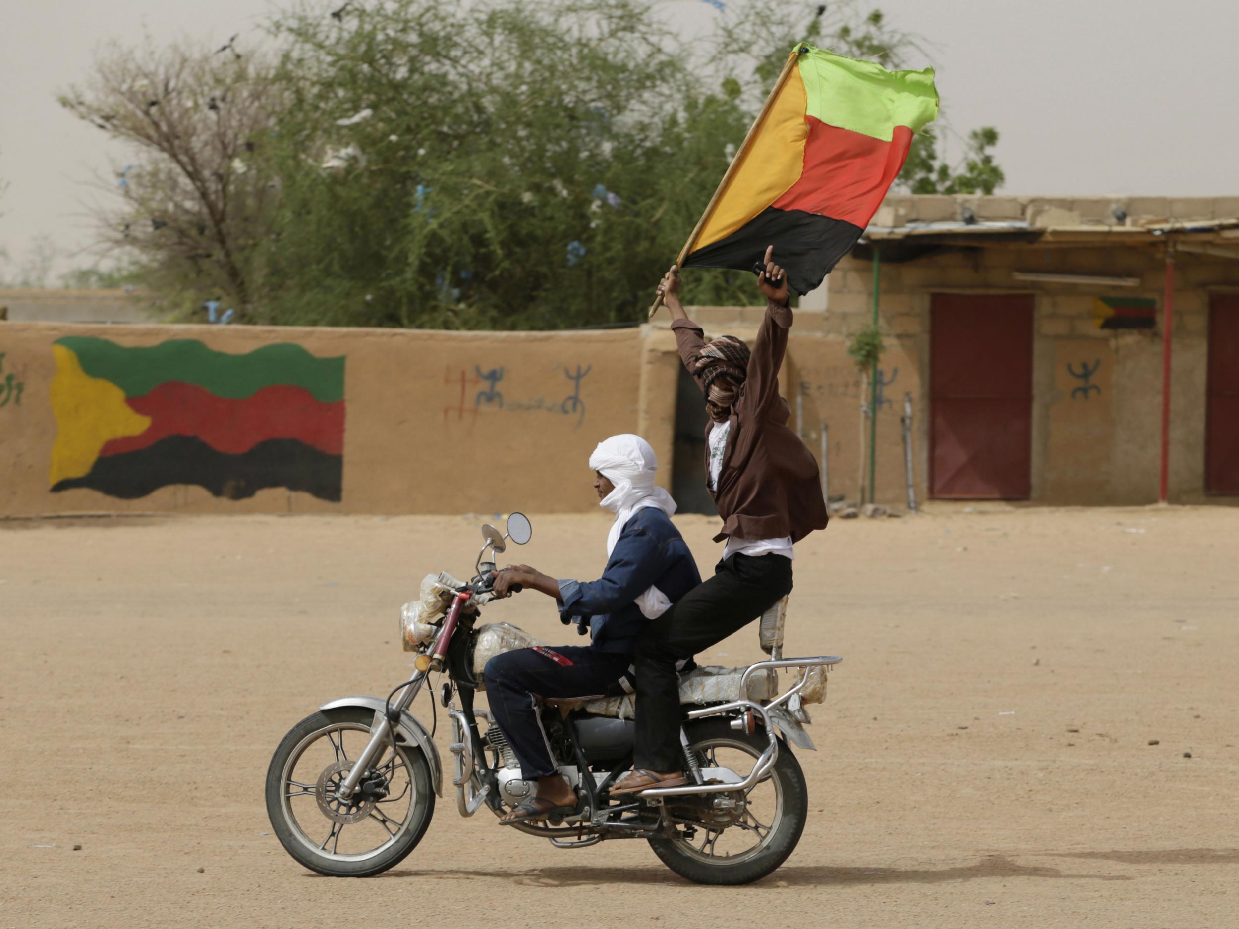 A Tuareg man waves the flag of the National Movement for the Liberation of Azawad (MLNA) during a demonstration in support of the MLNA in 2013