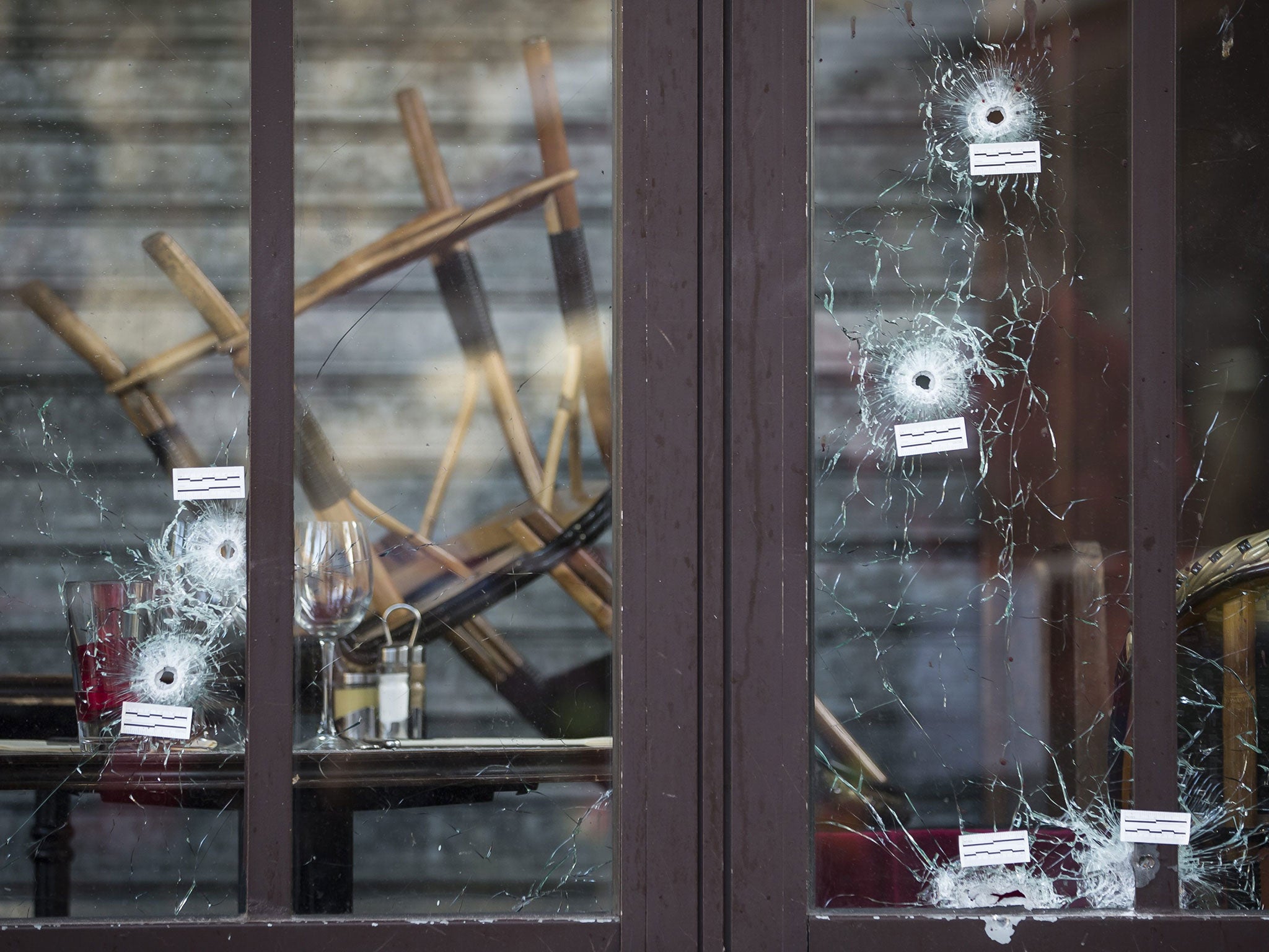 Bullet holes are seen in the terrace windows of Cafe Bonne Biere, as people lay flowers and candles in front, in Paris, France, 15 November 2015.