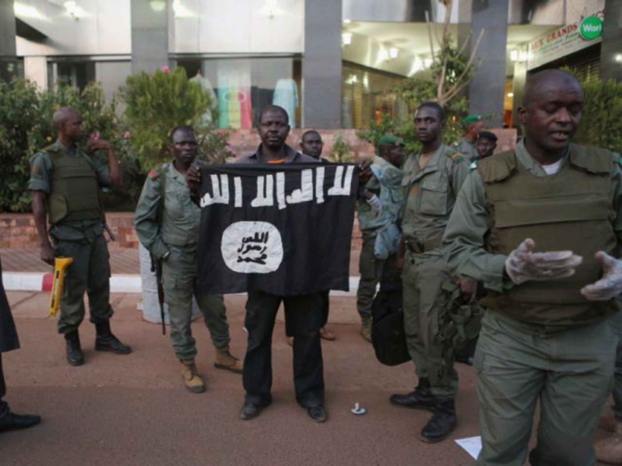 Malian security officials show a jihadist flag they said belonged to attackers in front of the Radisson hotel in Bamako