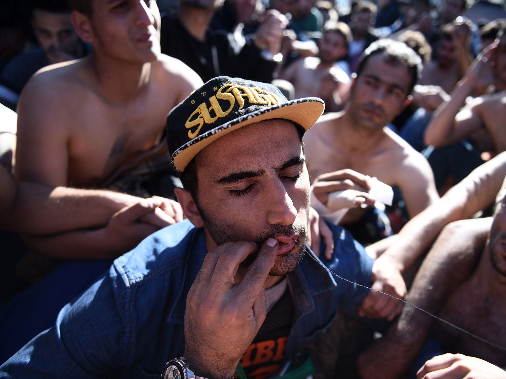 An Iranian refugee sews his mouth shut during a protest near the village of Idomeni at the Greek-Macedonian border, on Monday, Nov. 23, 2015.