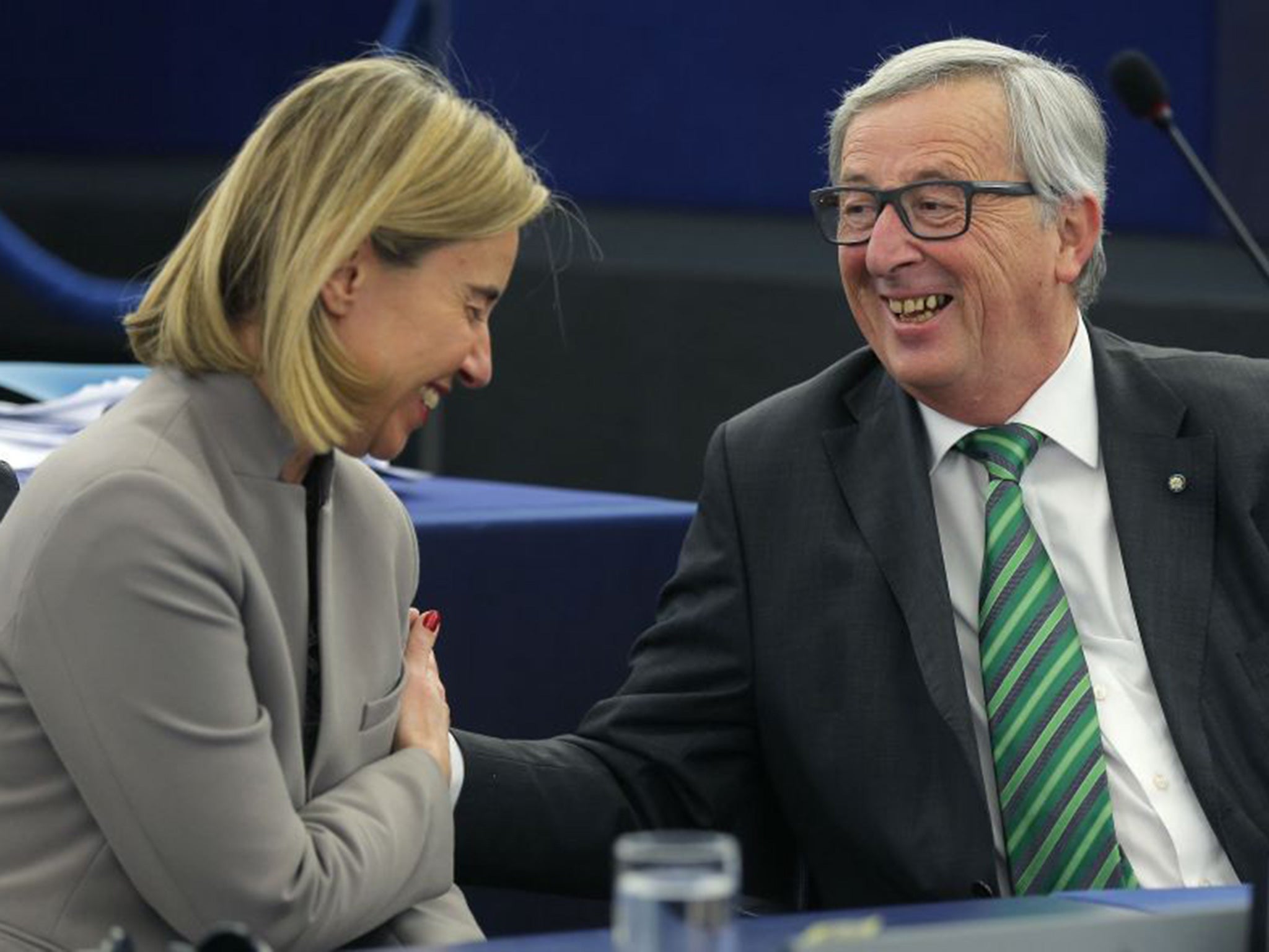 European Commission President Jean-Claude Juncker (R) jokes with European Union Foreign Policy Chief Federica Mogherini