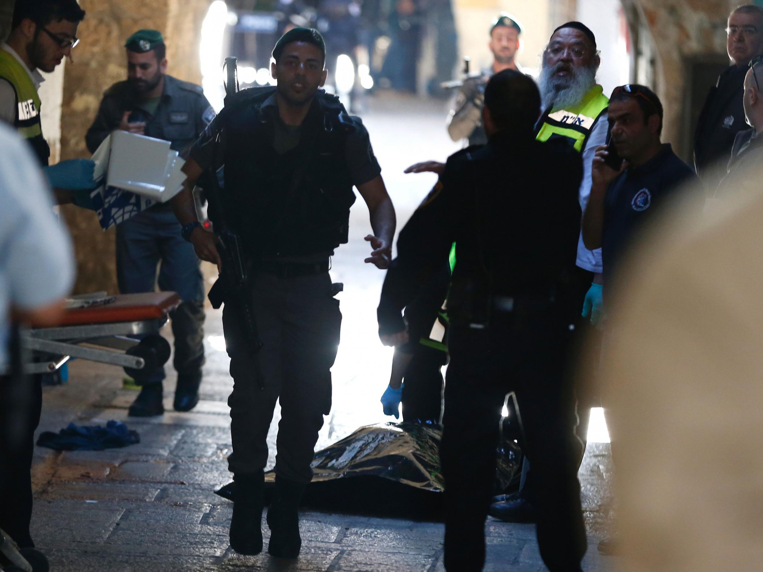 Israeli security forces and emergency personnel stand next to the covered body of Palestinian killed by border police