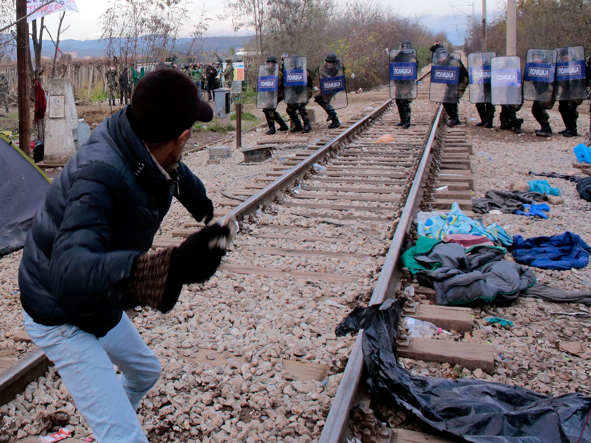 Migrants hurl stones at Macedonian policemen during clashes as the migrants protest against the building of a metal fence at the Greek-Macedonian border