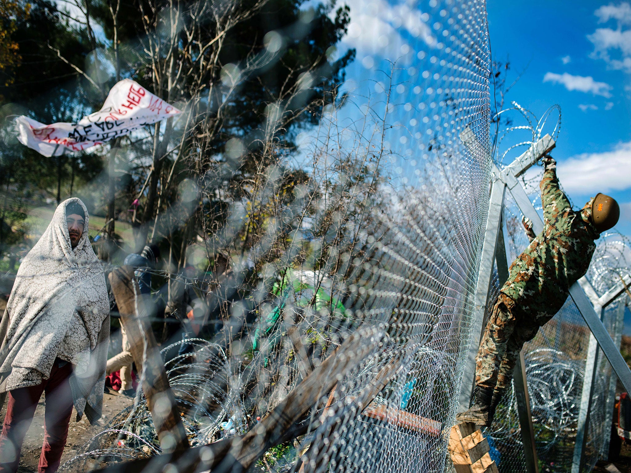 A migrant demonstrate looks on from behind a fence as he wait to cross the Greek-Macedonian border near Gevgelija