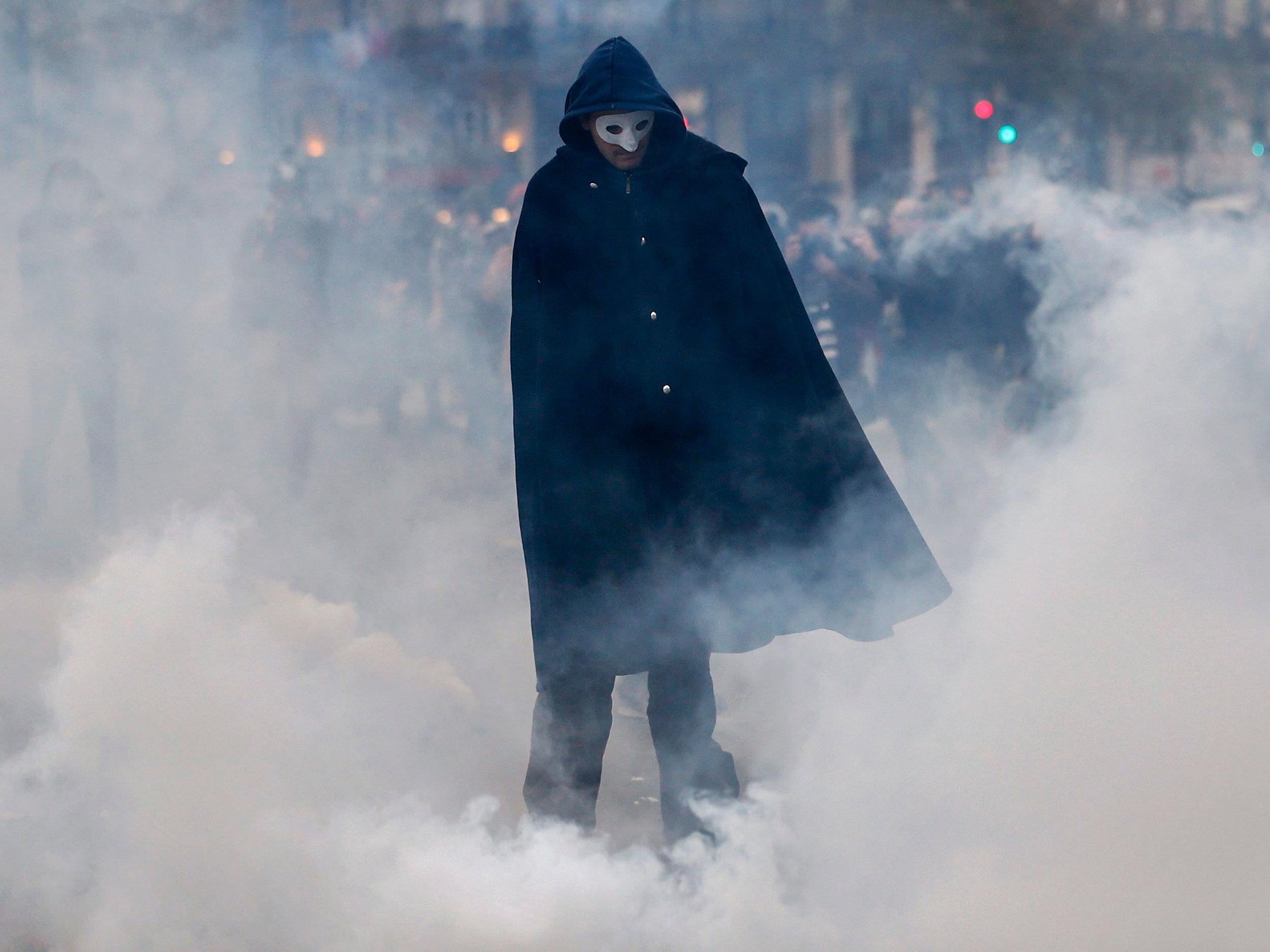 &#13;
A protester in a mask walks past smoke as demonstators clash with French riot police during on Place de la Republique ahead of the COP21 World Climate Change Conference&#13;