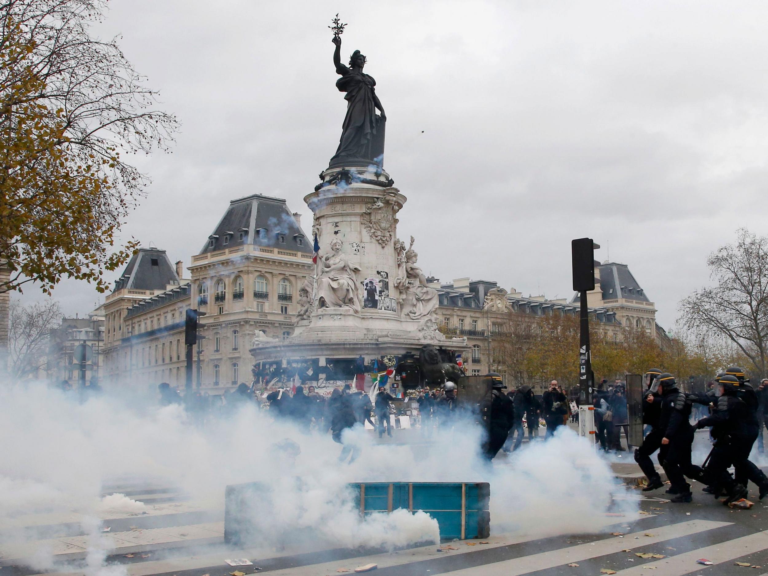 Clouds of tear gas fill the air as demonstrators clash with French CRS riot police at the Place de la Republique after the cancellation of the planned climate march