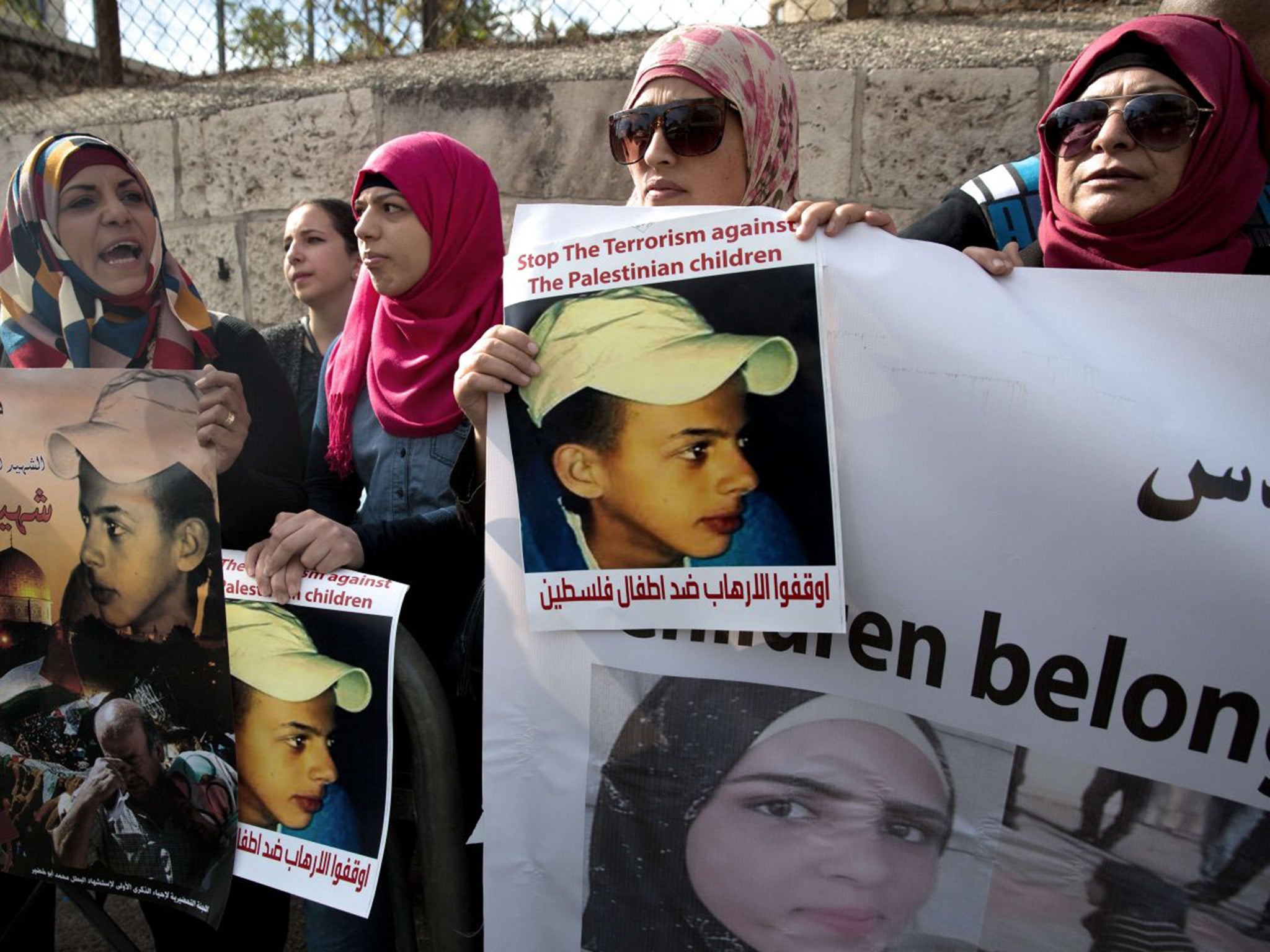 Protesters hold posters of Palestinian teenager Mohammed Abu Khdeir, who was killed last year, outside the district court in Jerusalem on November 30, 2015