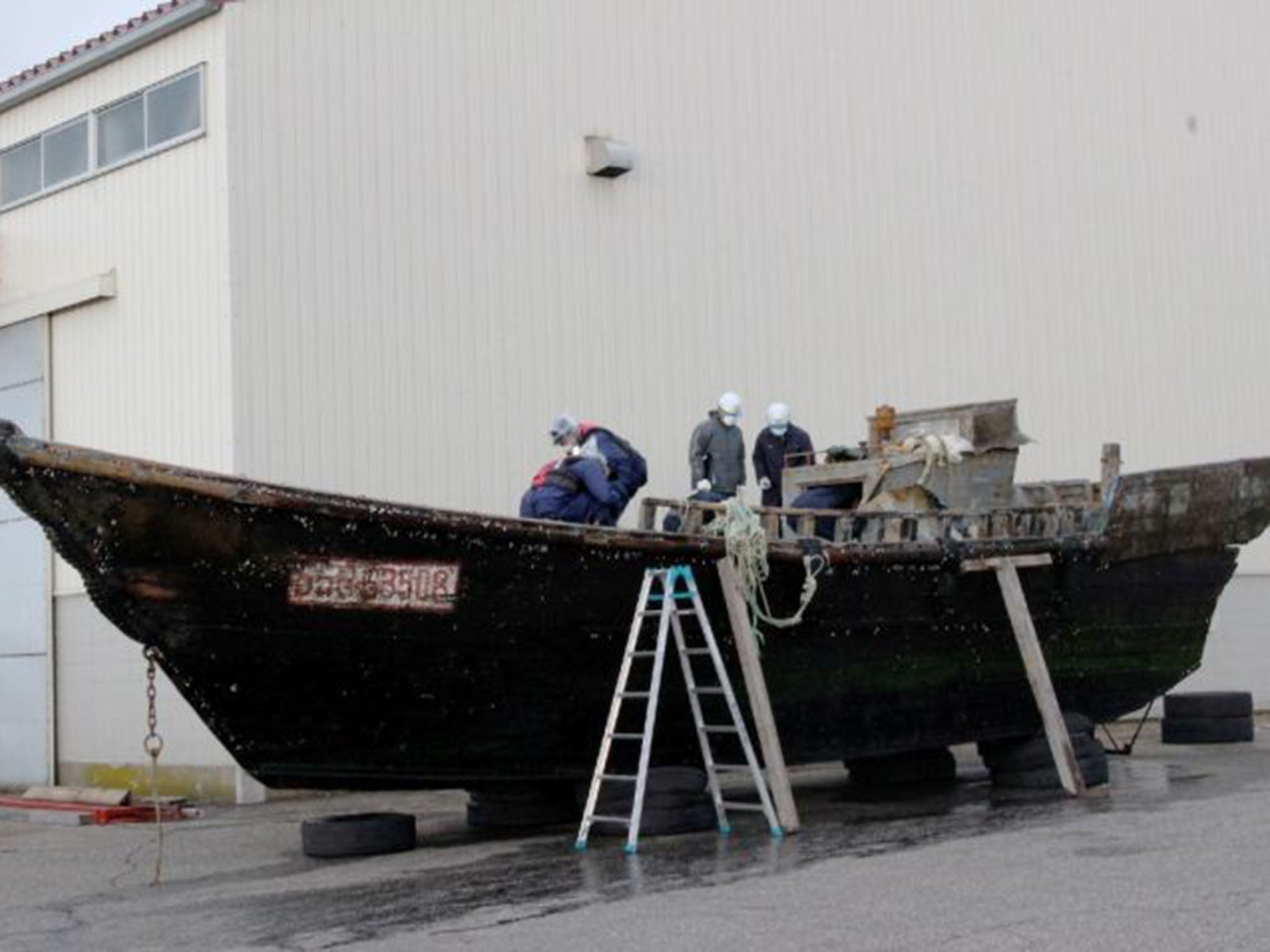 Coast guard officials investigating a wooden boat at the Fukui port, western Japan after the ship was found drifting off the coast of Fukui AFP