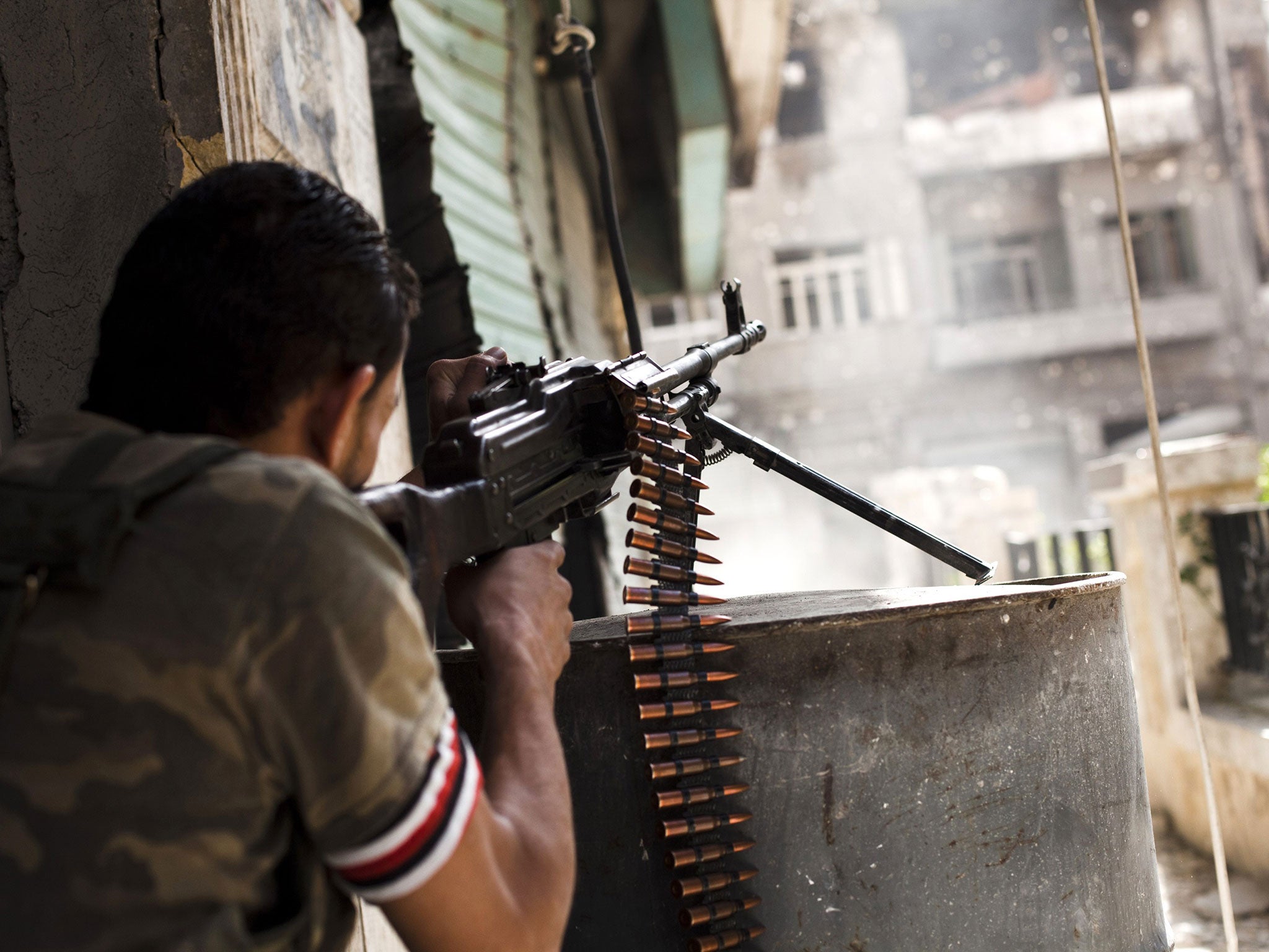 File: A rebel fighter fires his gun against a Syrian government troop position in the Bustan al-Basha area of the northern Syrian city of Aleppo