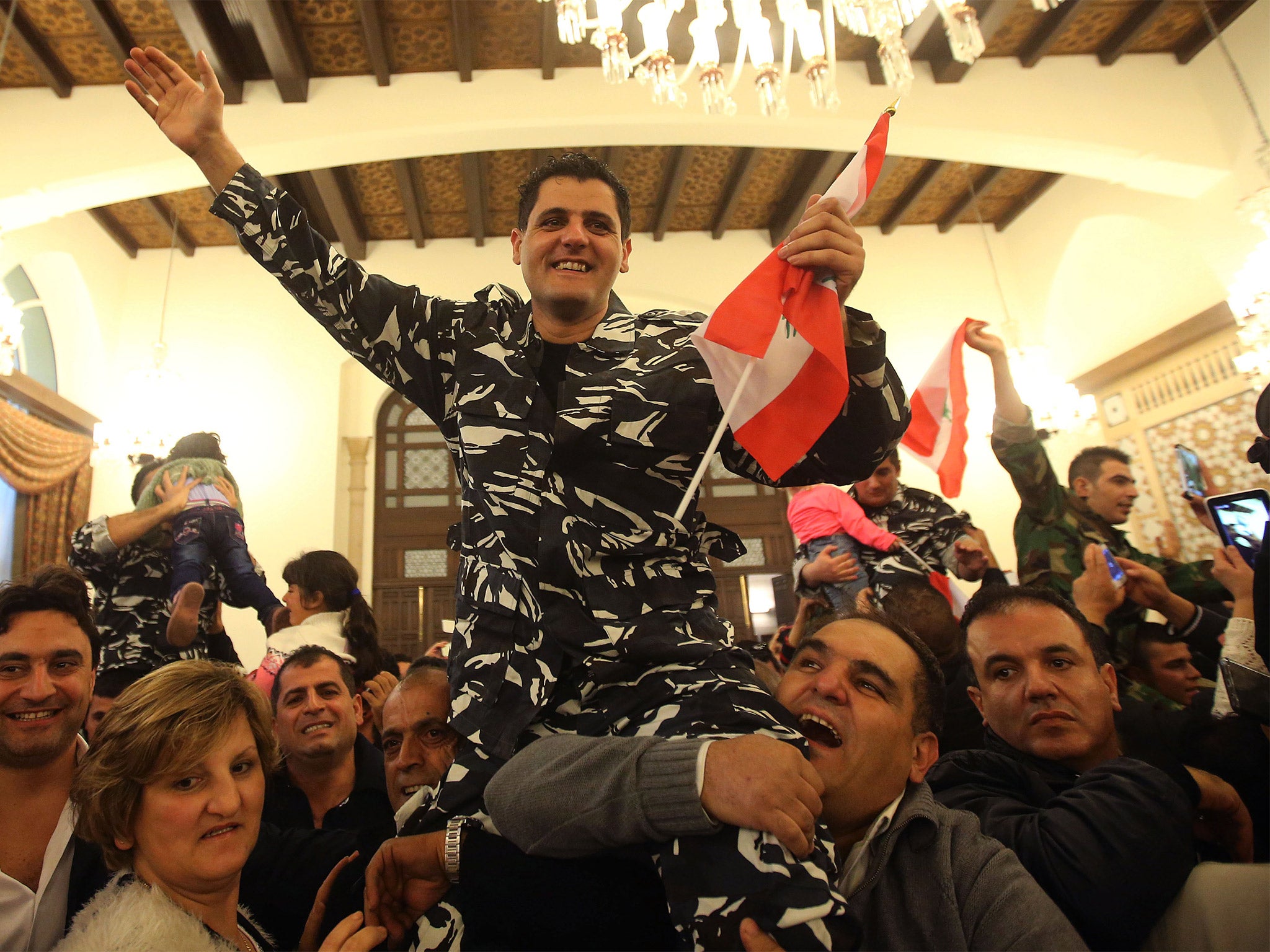 A Lebanese policeman who was kidnapped by Nusra Front, waves as he carried by his relatives upon his arrival at the government palace, in Beirut