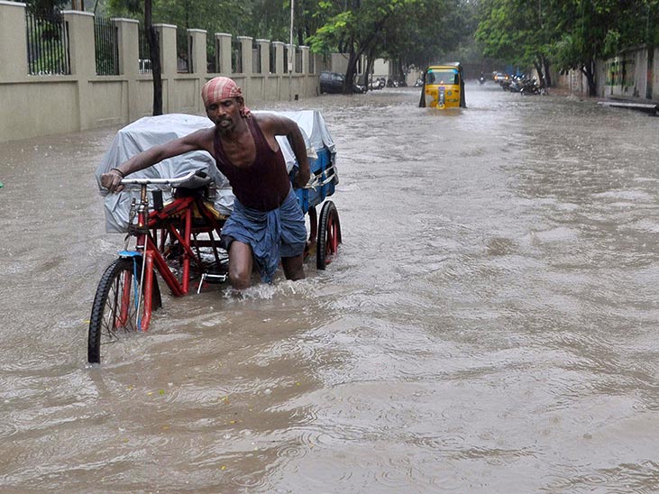 An Indian labourer pushes his cycle trishaw through floodwaters in Chennai during a downpour of heavy rain