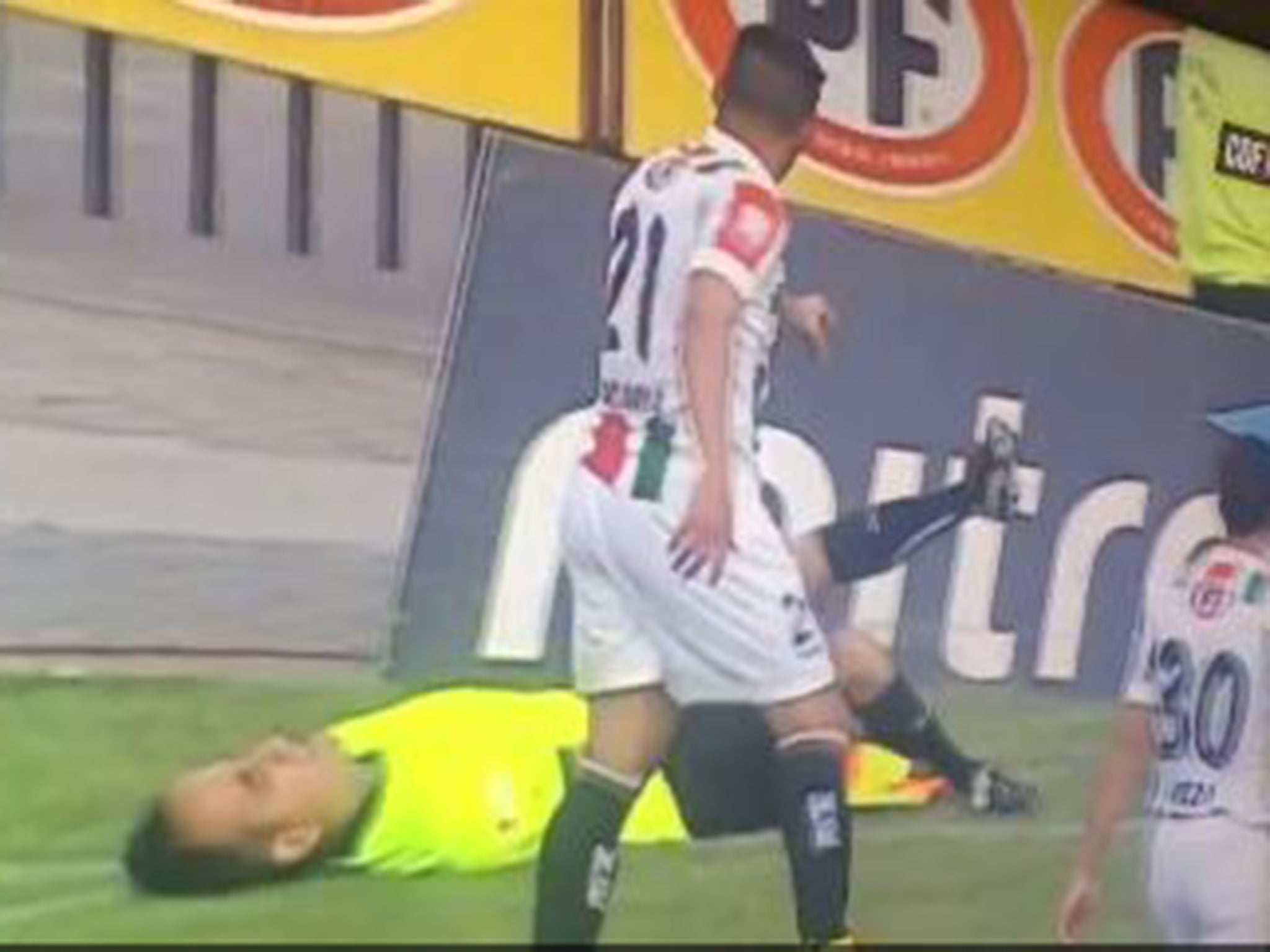 The linesman Carlos Echeverria holds his leg after the incident