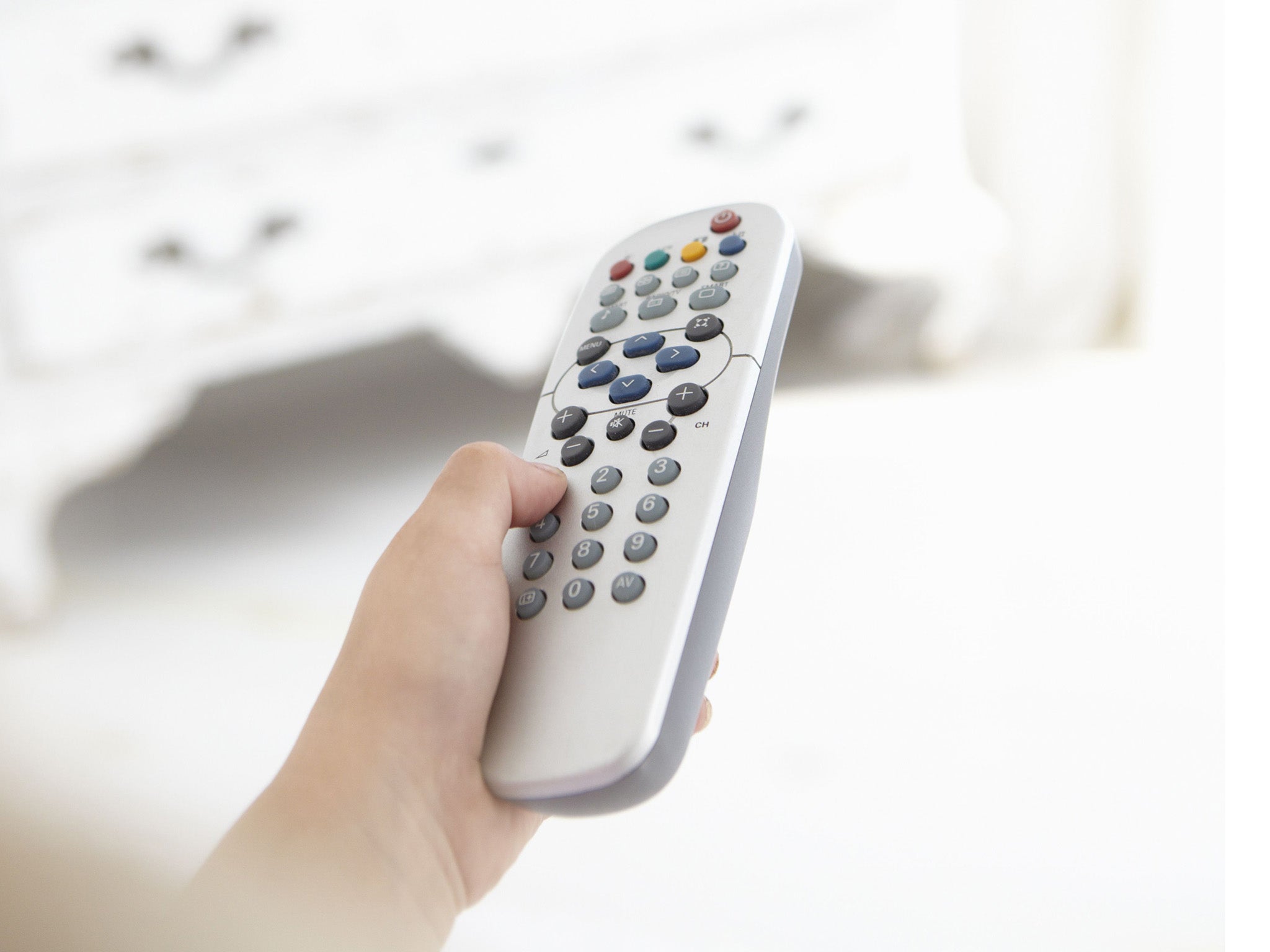 Young girl holding television remote control in bedroom