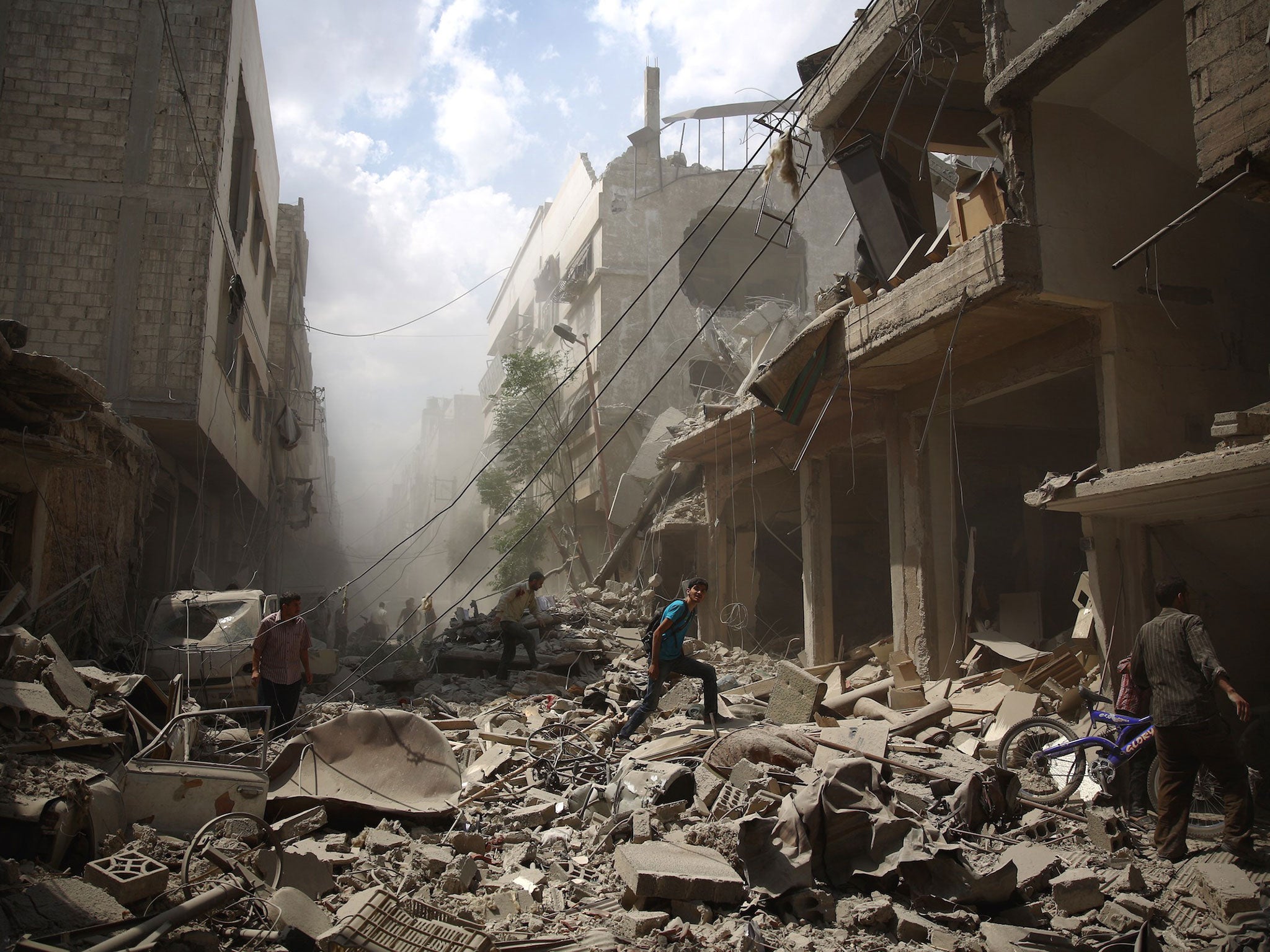 Syrians walk amid the rubble of destroyed buildings following reported air strikes by regime forces in the rebel-held area of Douma, east of the capital Damascus