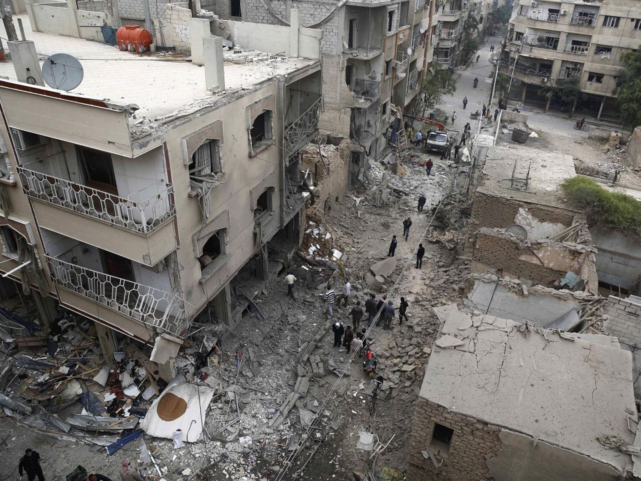 Syrians inspecting damaged buildings following an air strike in Douma