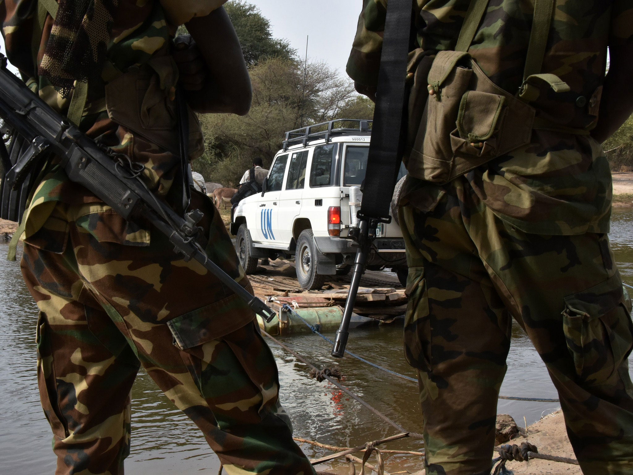 A picture taken on January 27, 2015 shows Chadian soldiers watching as a UN vehicle from a United Nations' refugee agency (UNHCR) convoy crosses a branch of lake Chad