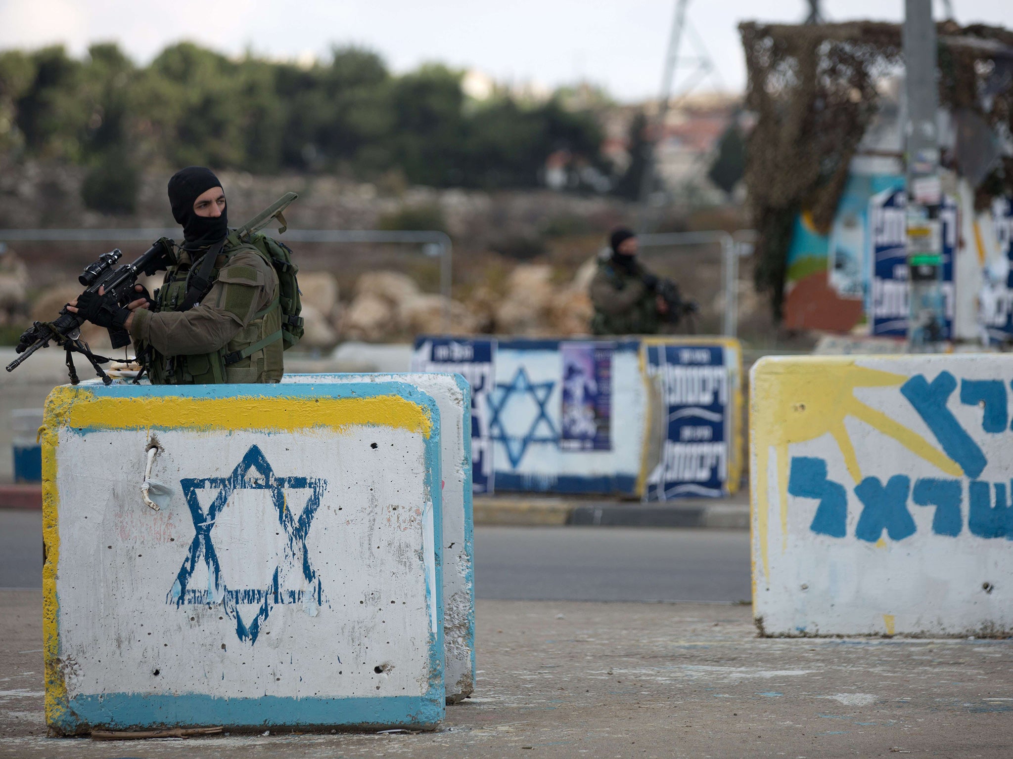 An Israeli soldier stands guard at a deserted junction between Jerusalem and Hebron