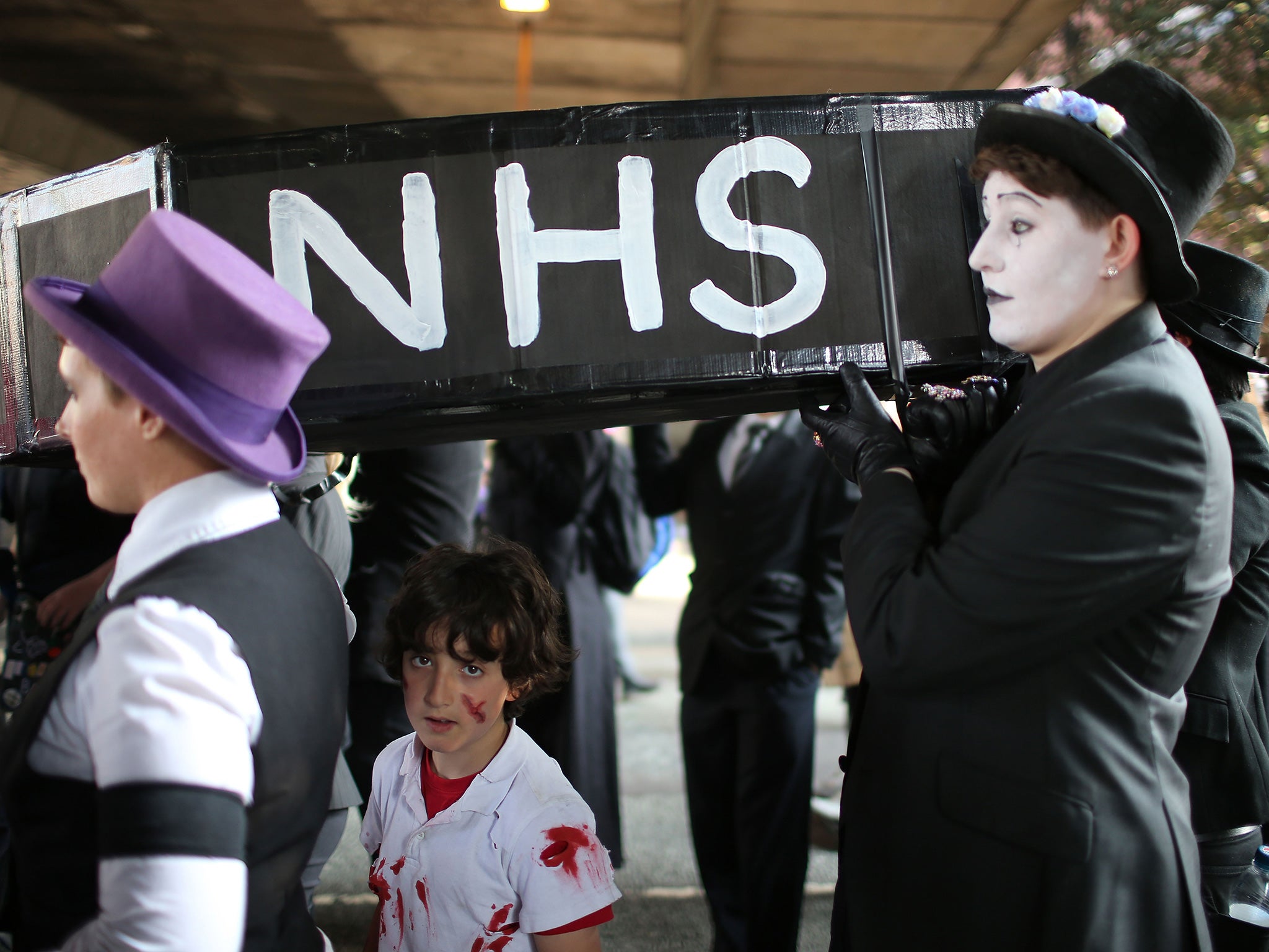 People carry a mock-up of a coffin with the letters 'NHS' on the side as they take part in an anti-austerity protest