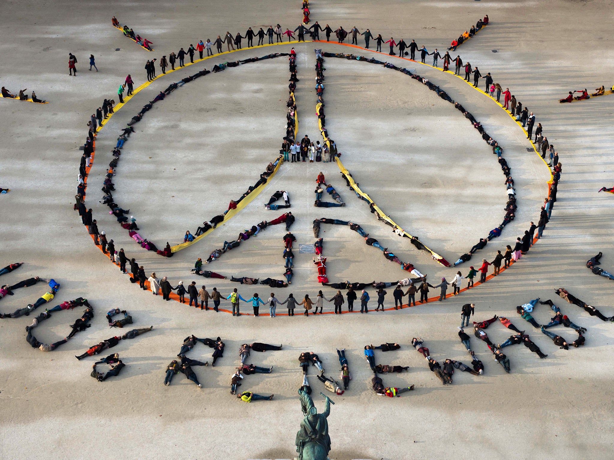 People make the "Pray for Paris" sign along with the slogan "100 percent renewable" in Paris, on the sidelines of the COP21 climate change conference