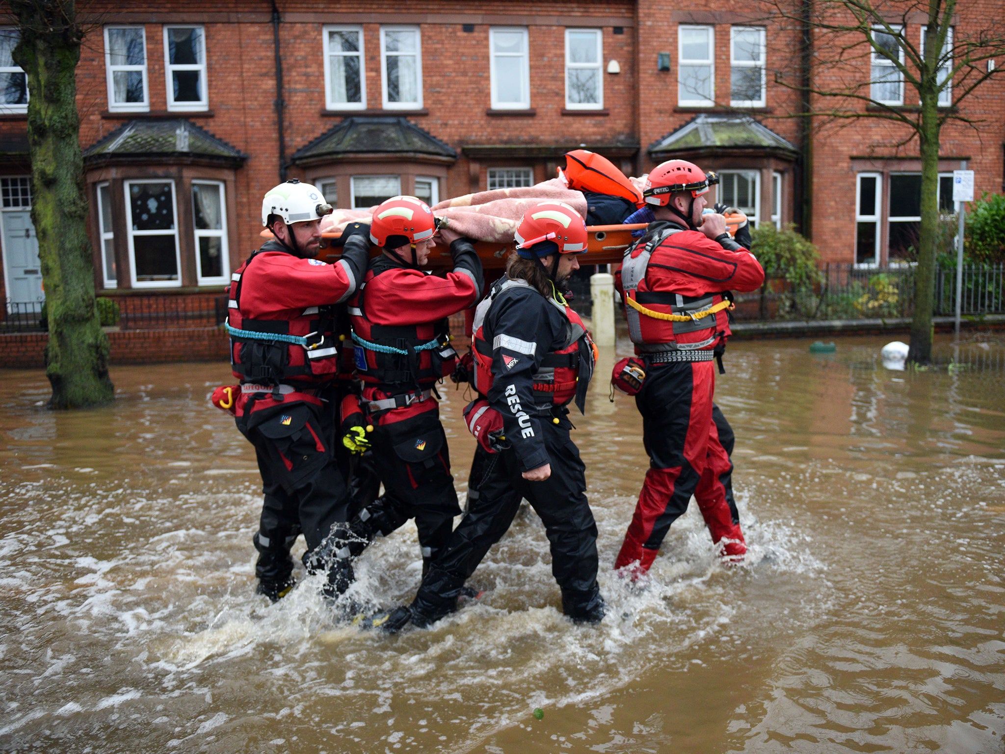 Members of the emergency services carry an elderly resident aloft as they rescue her from a flooded property in Carlisle