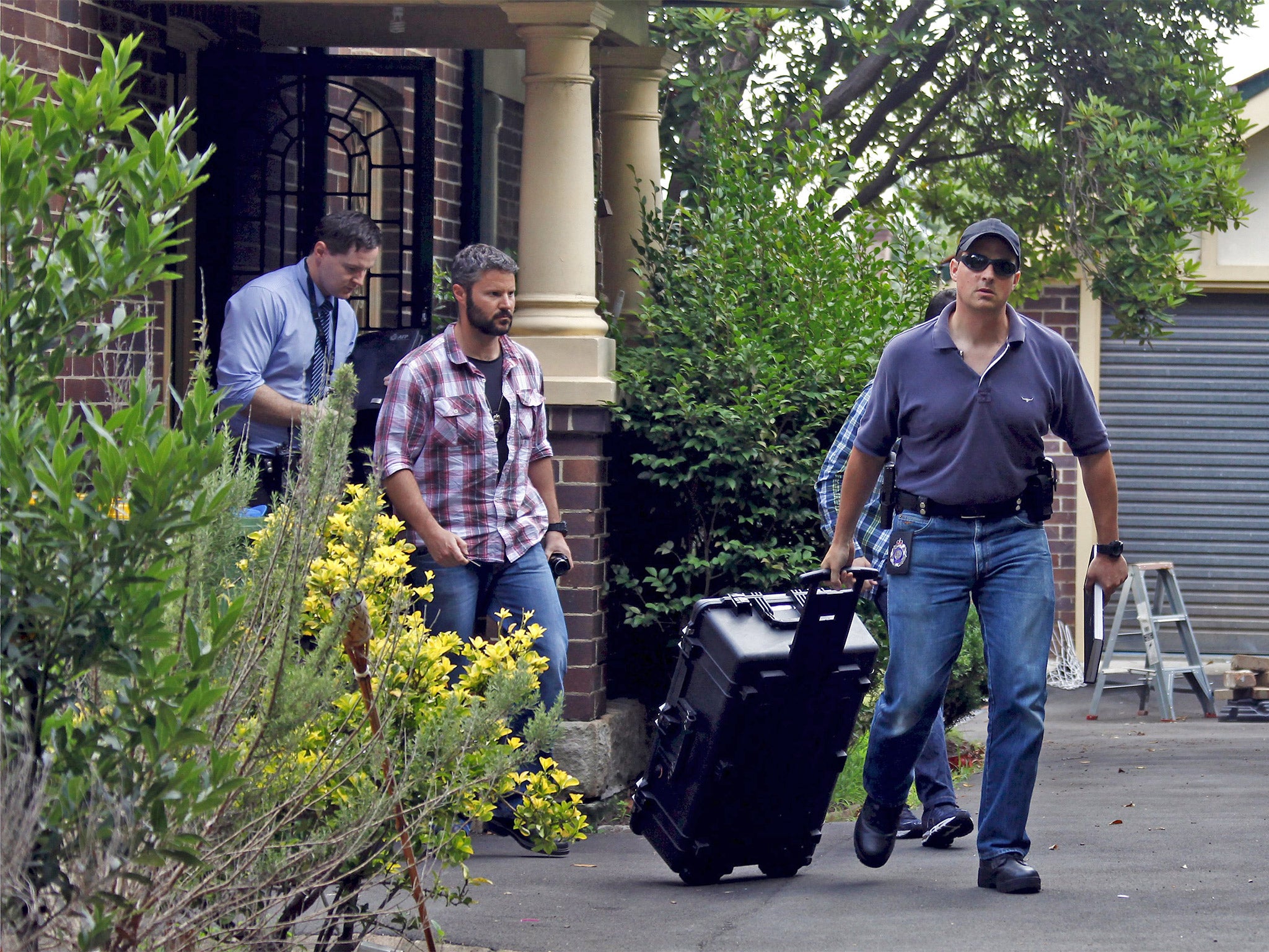 Australian Federal Police officers walk down the driveway after searching the home of Craig Wright in Sydney