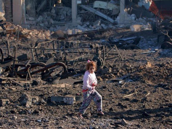 A girl walks over debris at a site hit by one of 3 three truck bombs