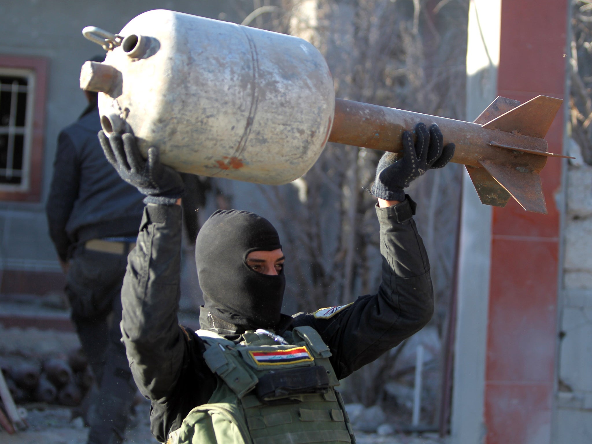 A member of the Iraqi counter-terrorism forces carries a rocket, locally made from domestic gas canisters, from an arms depot that belonged to Islamic State