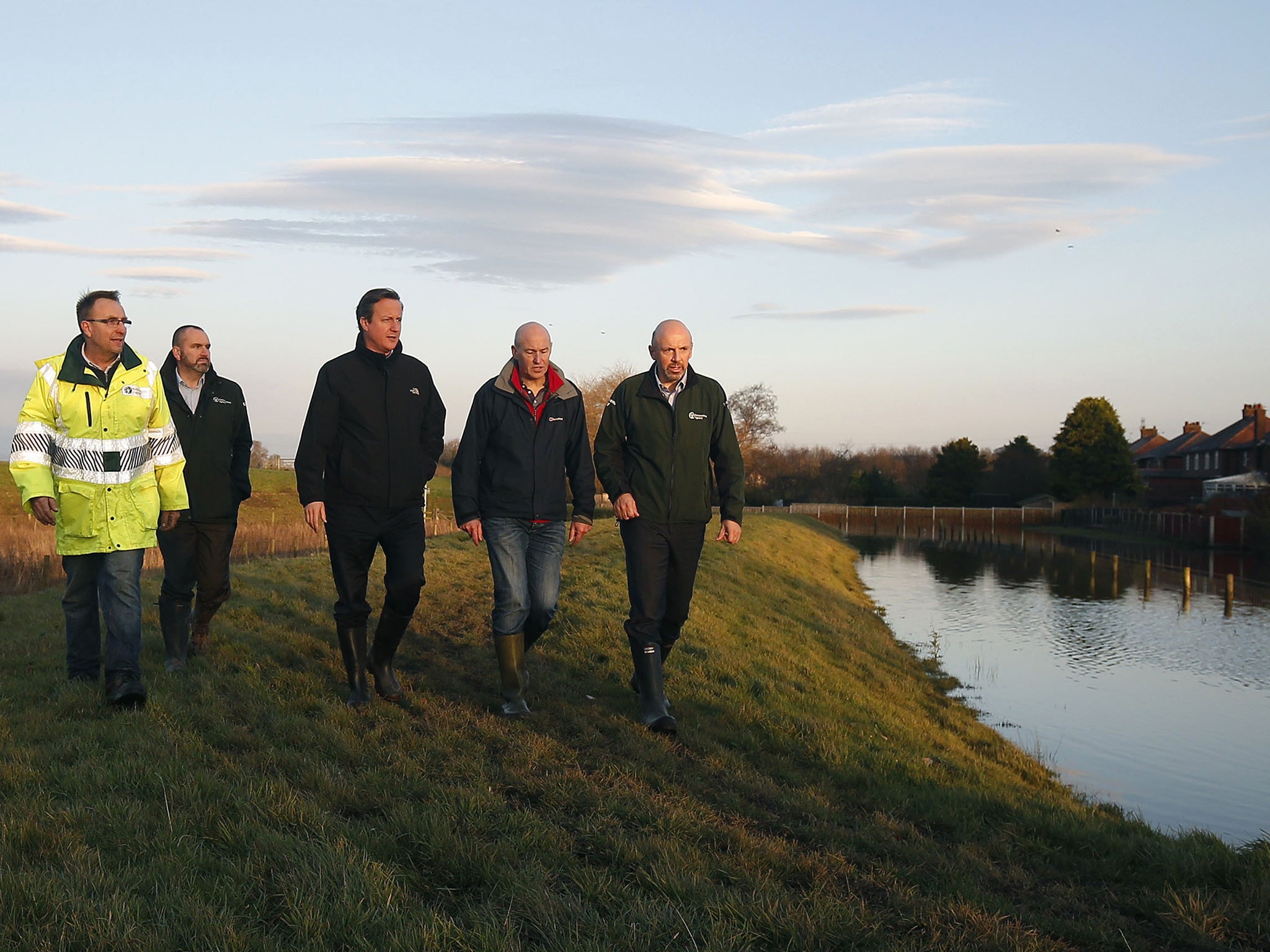 British Prime Minister David Cameron, centre, looks at the flood defence system in Carlisle as residents began sweeping out homes and businesses in the wake of Storm Desmond