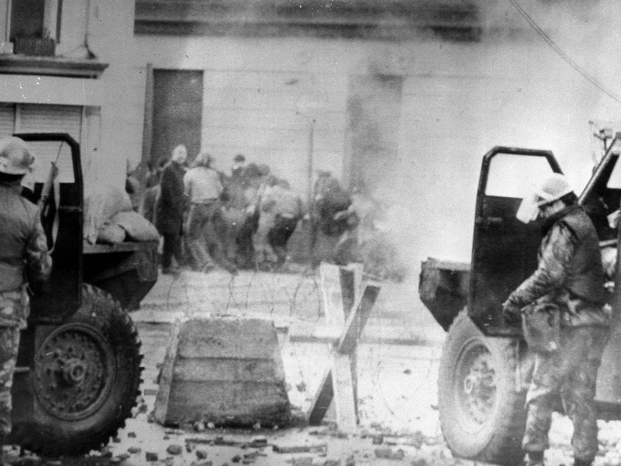 Soldiers taking cover behind their sandbagged armoured cars while dispersing rioters with CS gas during protests in Londonderry