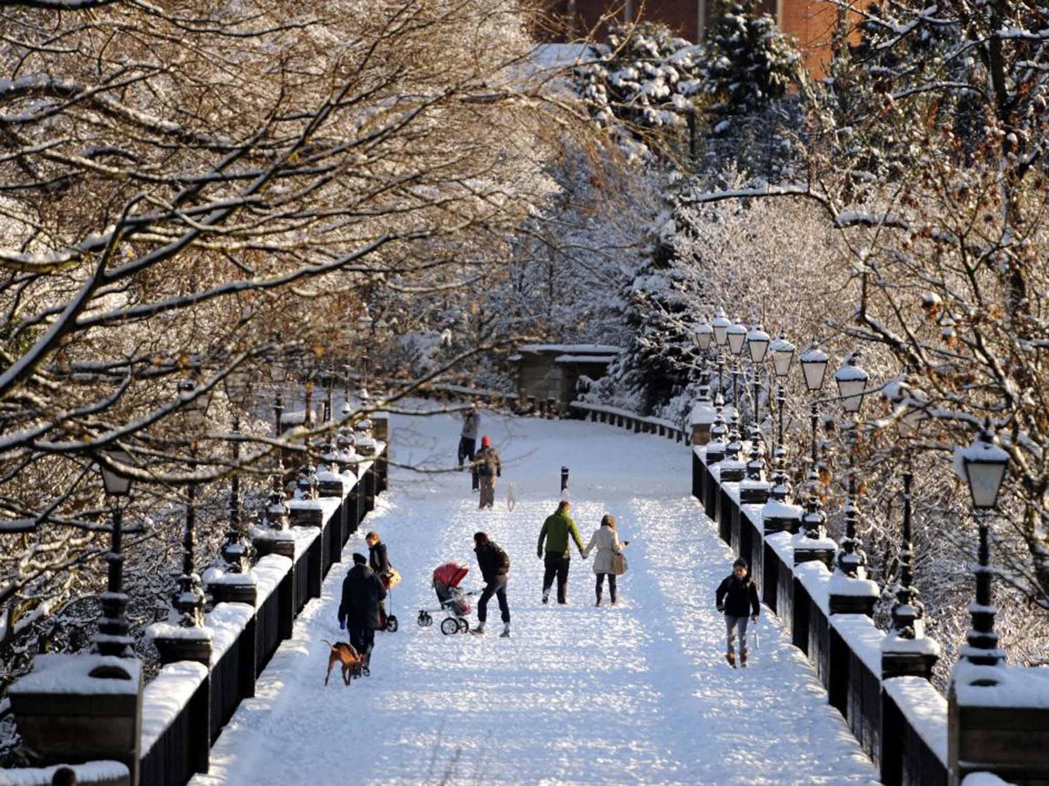 Walkers cross a snow-covered bridge