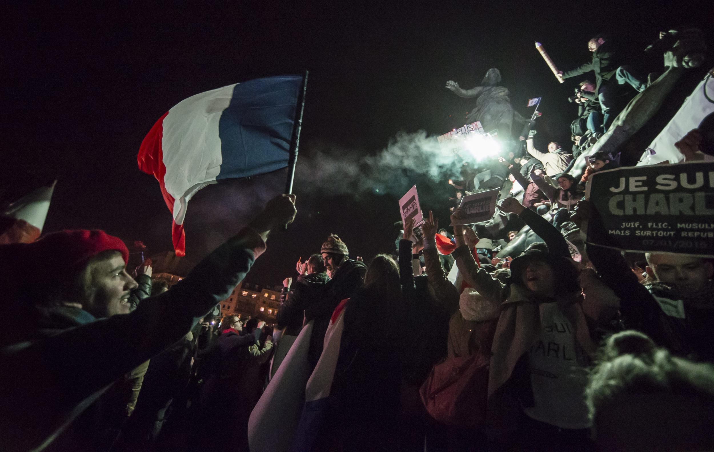 People gather around the monument on Place de la Nation as millions of people march against terrorism in Paris