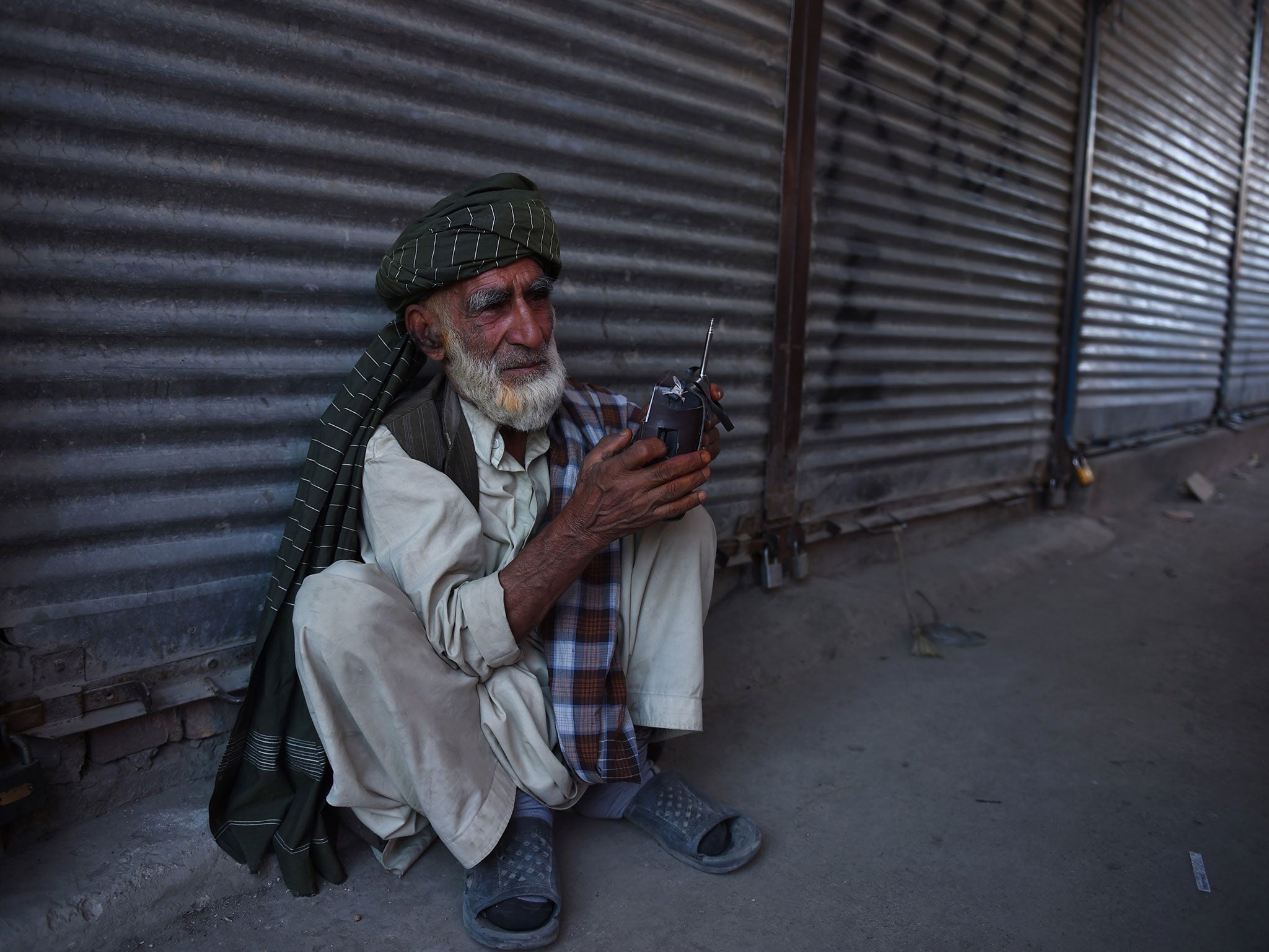 An elderly Afghan man listens to a radio early in the morning in Kabul on 16 July, 2015