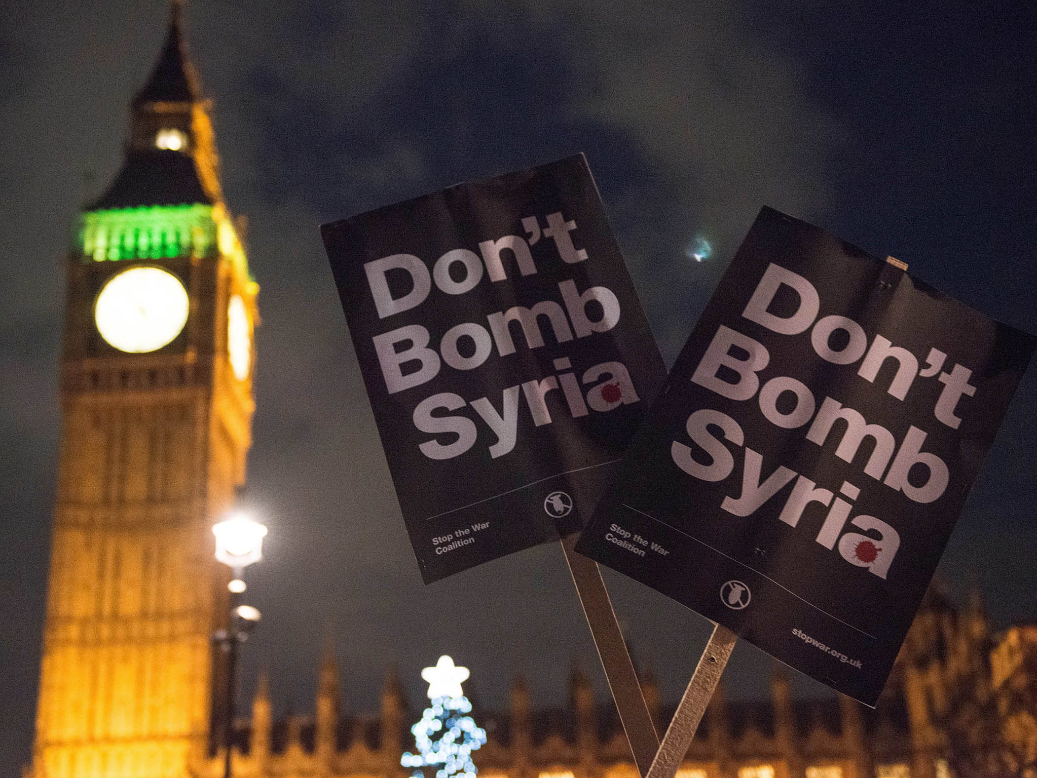 Demonstrators hold "Don't Bomb Syria" placards as they protest outside the Houses of Parliament