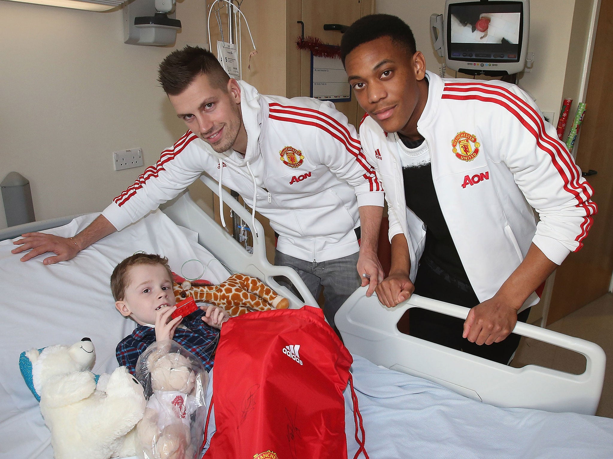 Manchester United players Morgan Schneiderlin and Anthony Martial give out presents to children in hospital