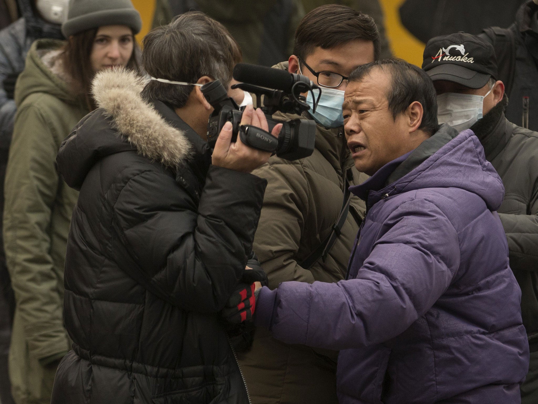 A man pushes a videojournalist, left, near the Beijing No. 2 People's Intermediate Court where human rights lawyer Pu Zhiqiang was sentenced in Beijing, China, Tuesday, Dec. 22, 2015.