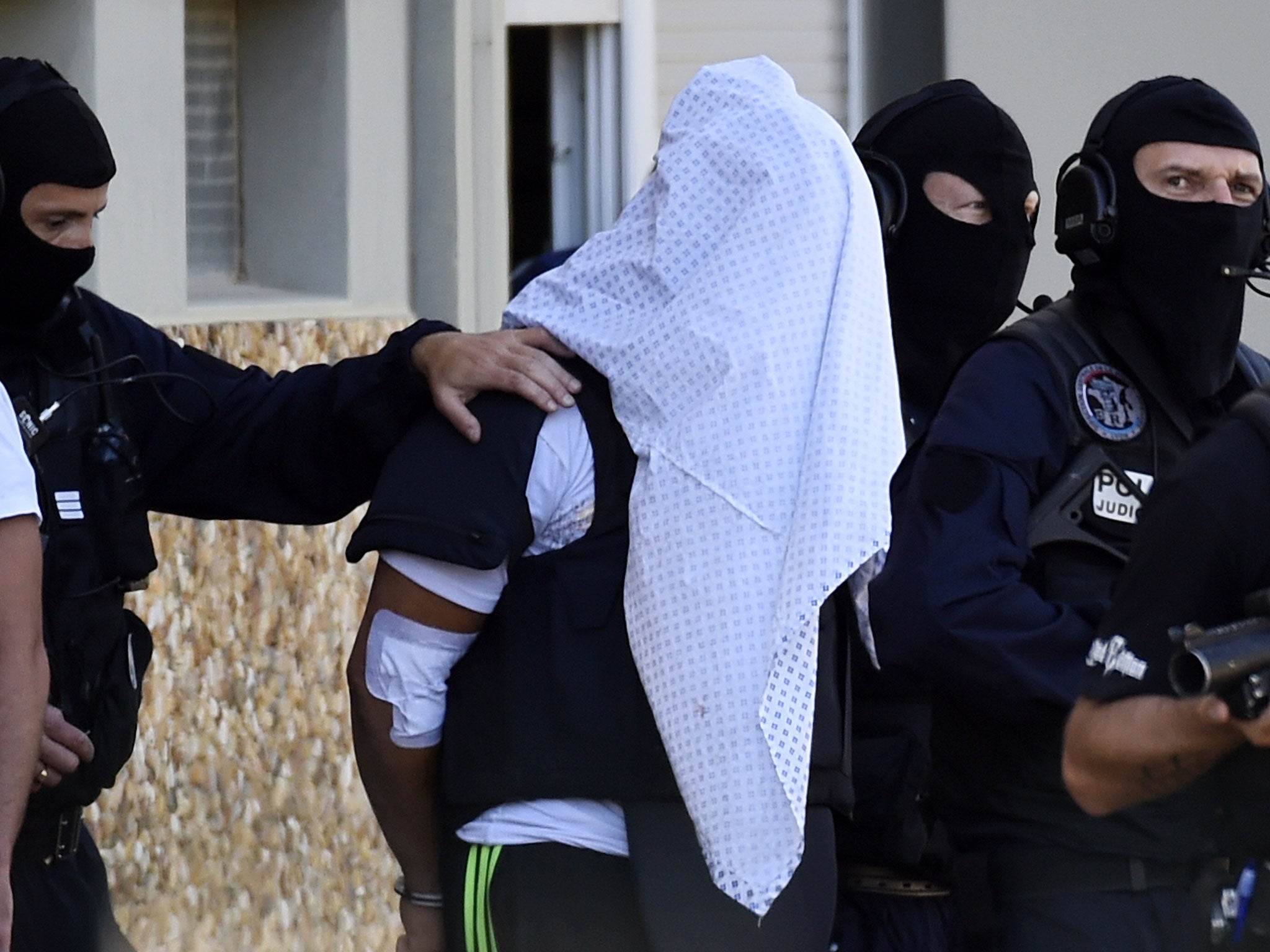 French police escort Yassin Salhi (C), a man suspected of decapitating his boss in an attack on a gas factory, as they leave his flat in Saint-Priest on June 28, 2015