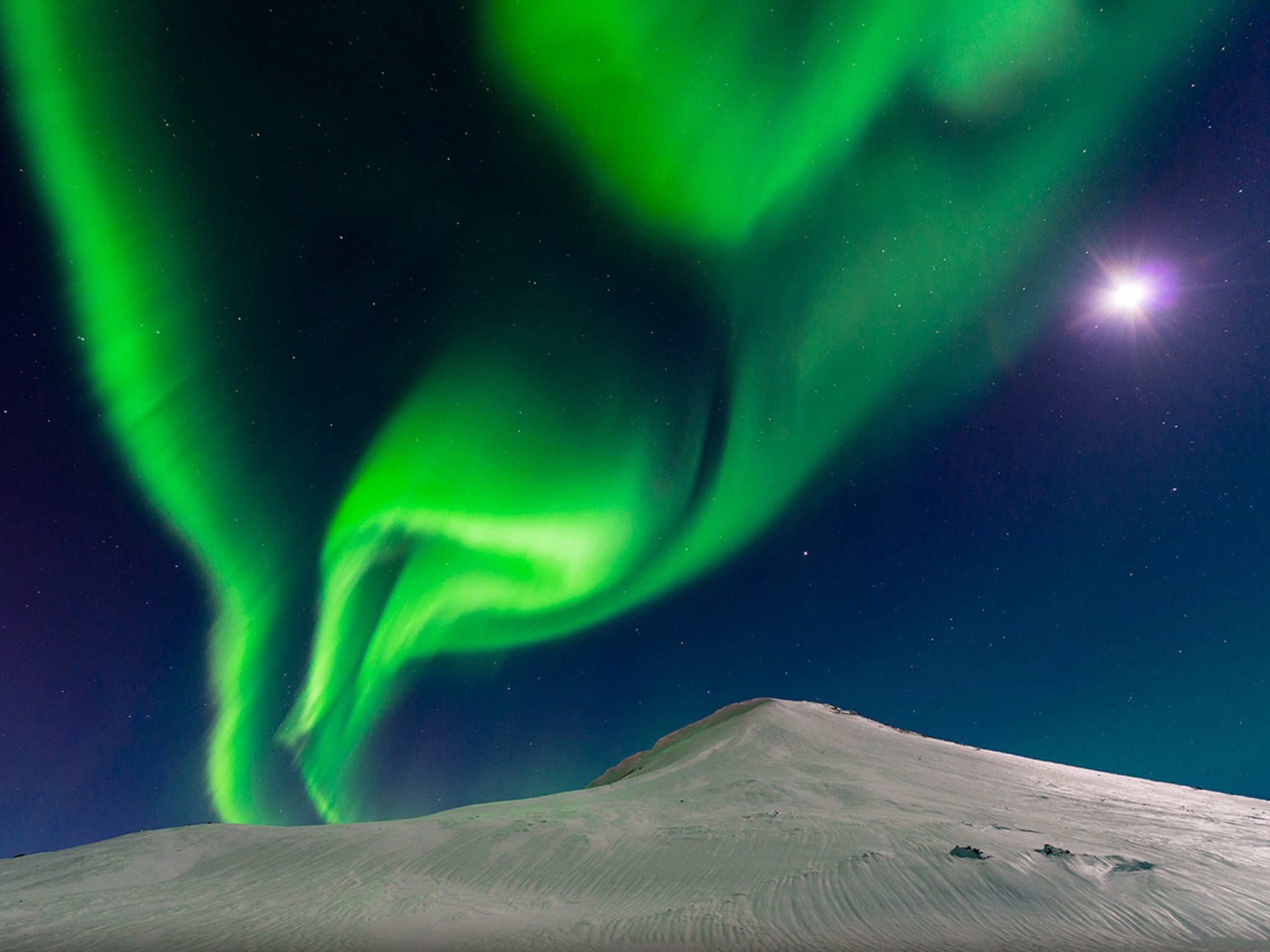 "Dancing With the Moon" by Andrew George: The aurora borealis shares the sky with a bright moon in Iceland. Named for the Roman goddess of dawn, the vivid beams of light result from collisions between charged particles released from the sun’s atmosphere and gaseous particles in Earth’s atmosphere