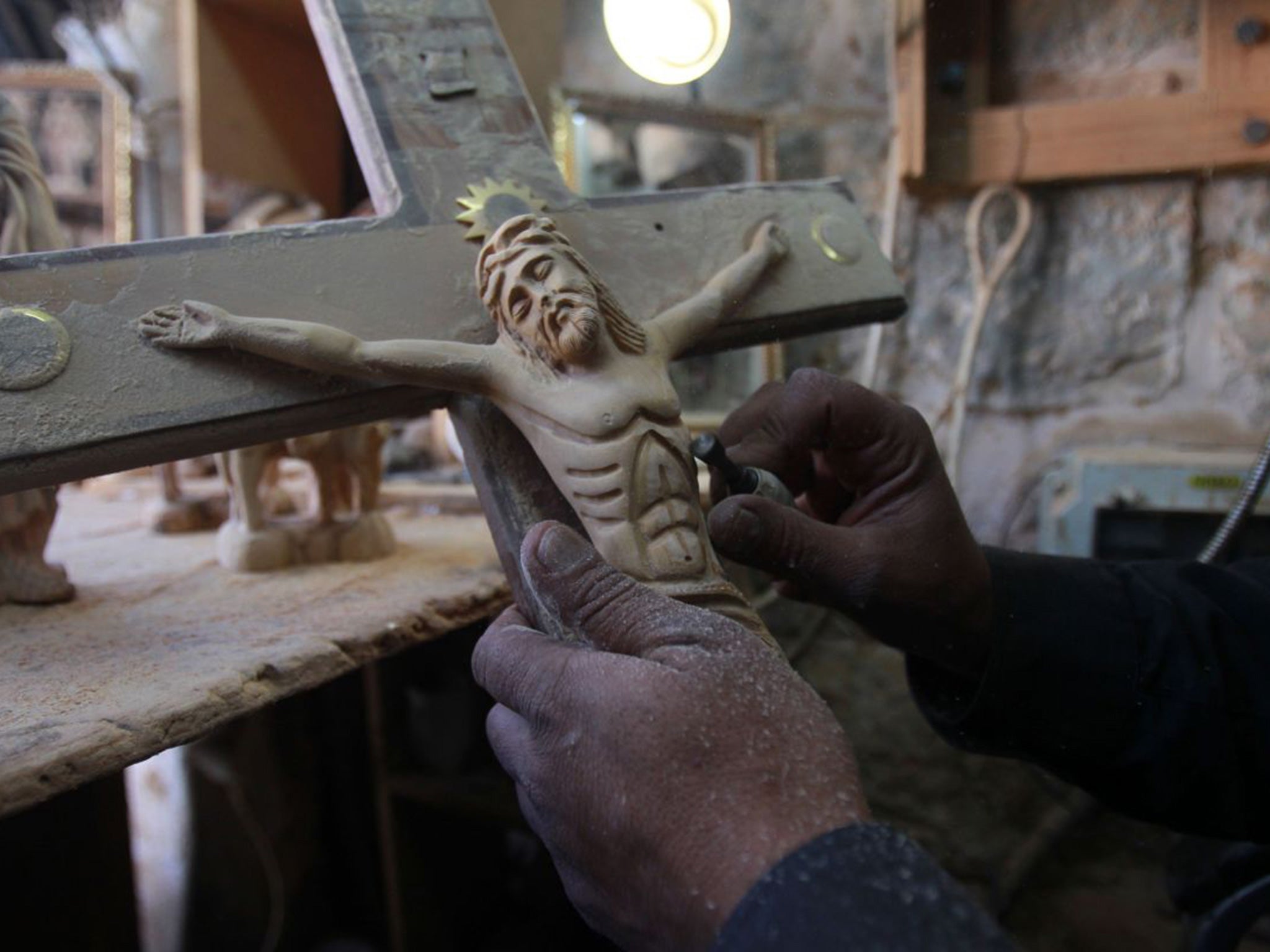 A Palestinian wood sculptor works on an olive wood crucifix at his workshop near Manger Square in the West Bank biblical city of Bethlehem