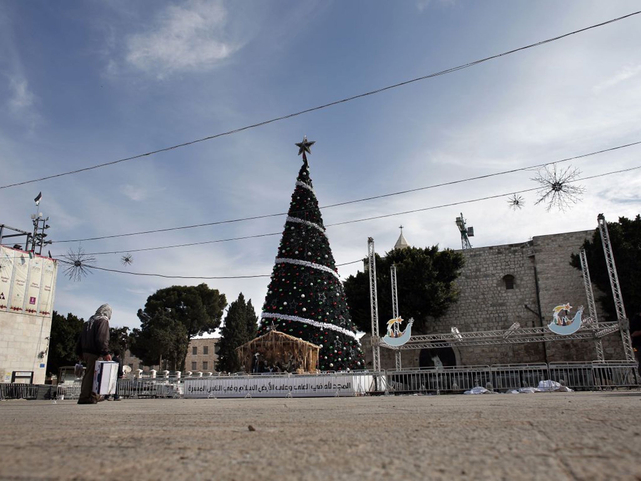 A man walks past a Christmas tree on the Manger Square