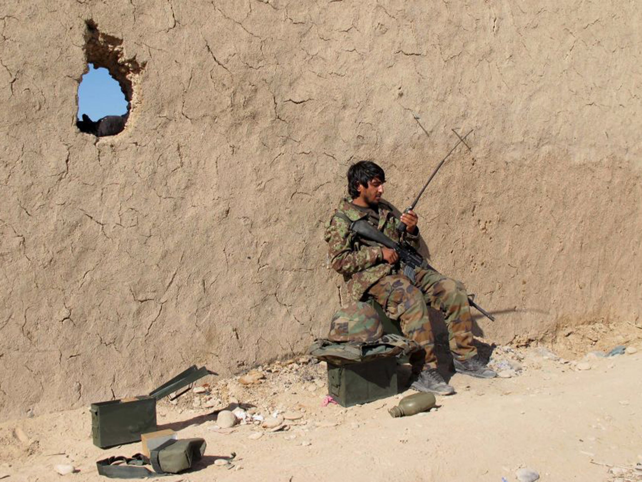 An Afghan National Army (ANA) soldier speaks on a radio at an outpost during the defense of Sanjin